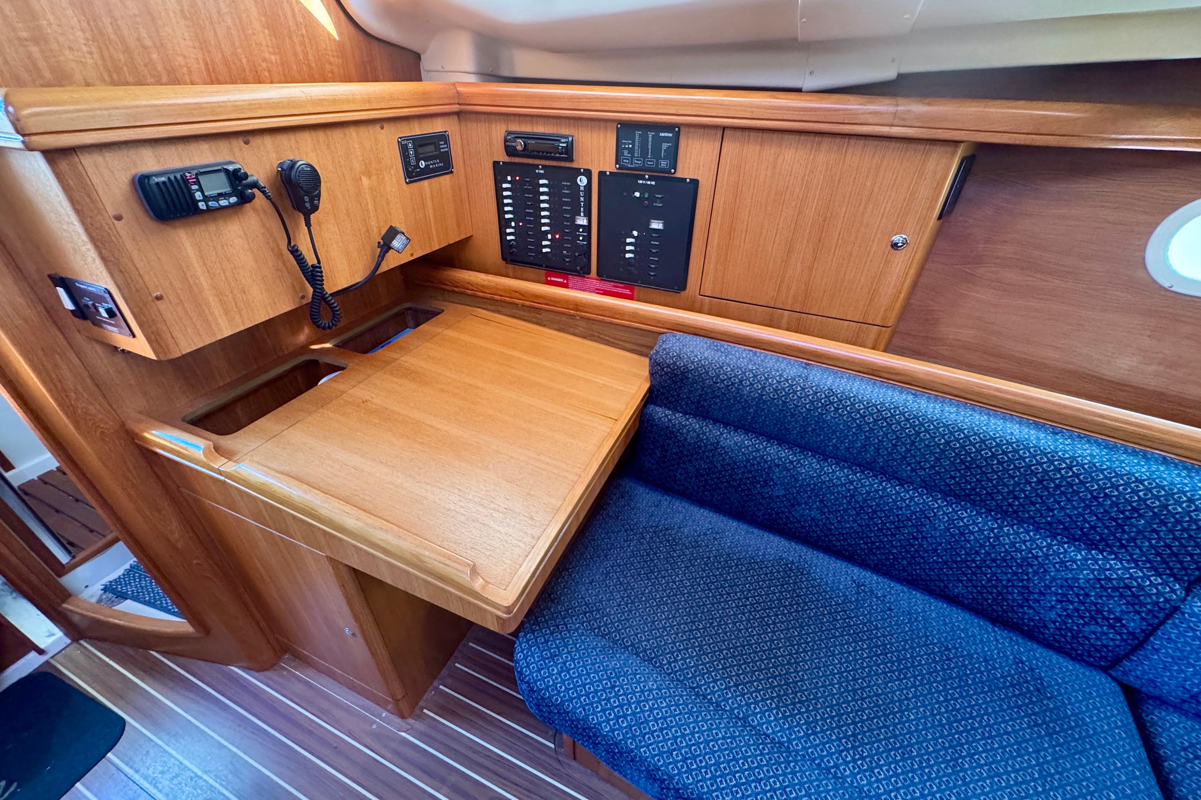 Interior of 2003 Hunter 36 sailboat with navigation station and blue cushioned seating.
