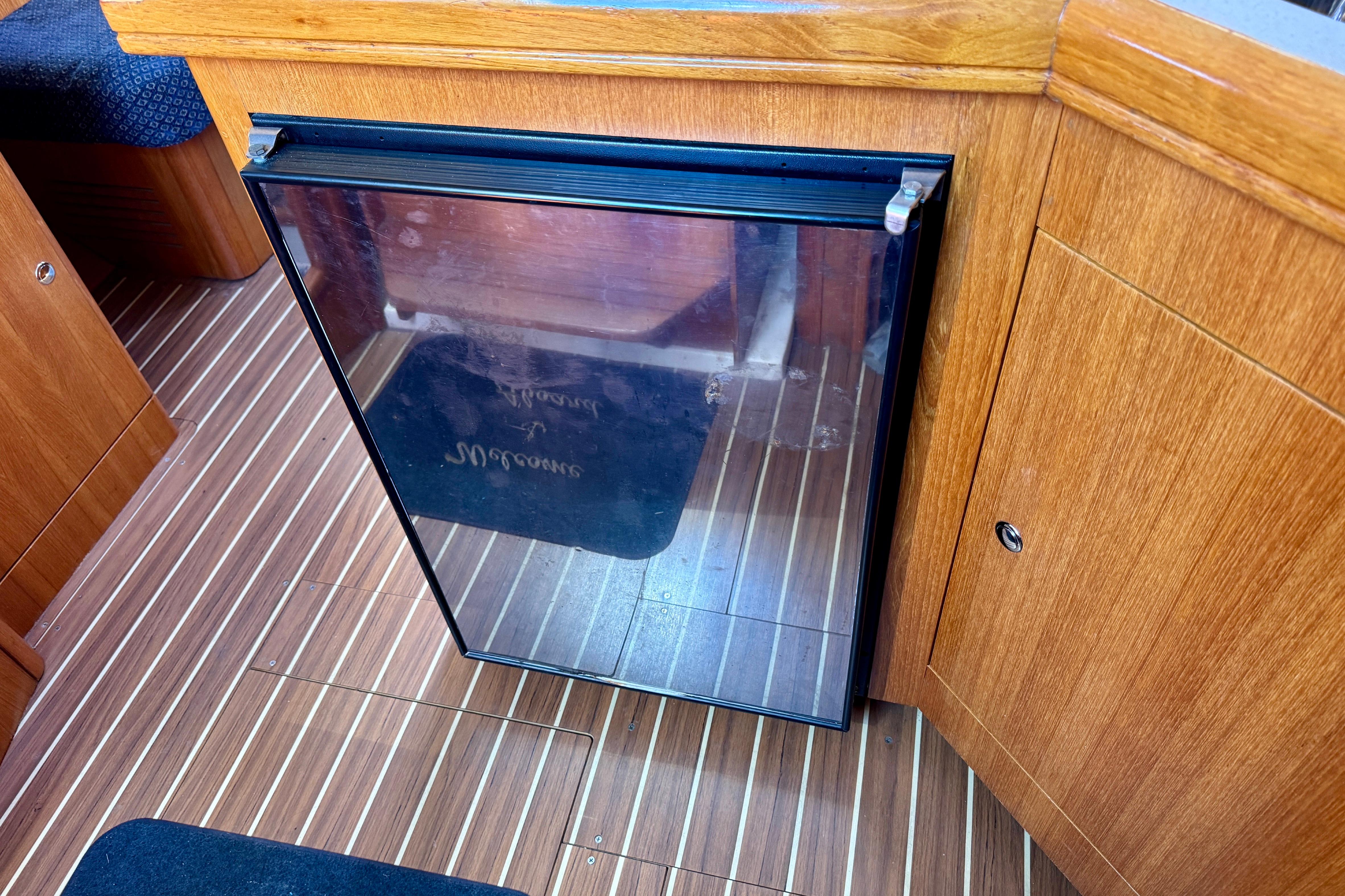 Wooden interior of a 2003 Hunter 36 yacht with a compact fridge.