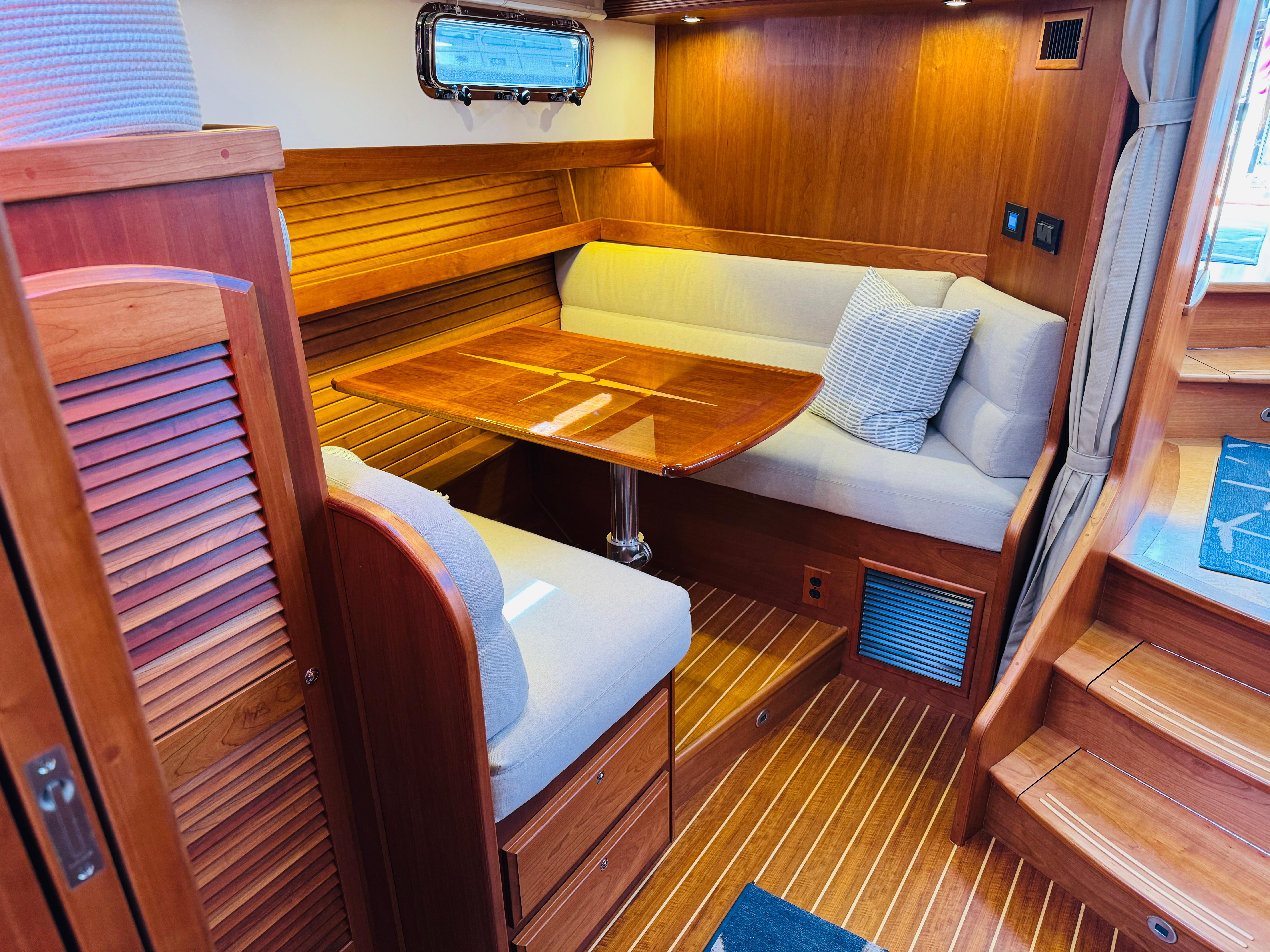2018 Sabre 42 Salon Express interior with wooden dining area and cushioned seating.