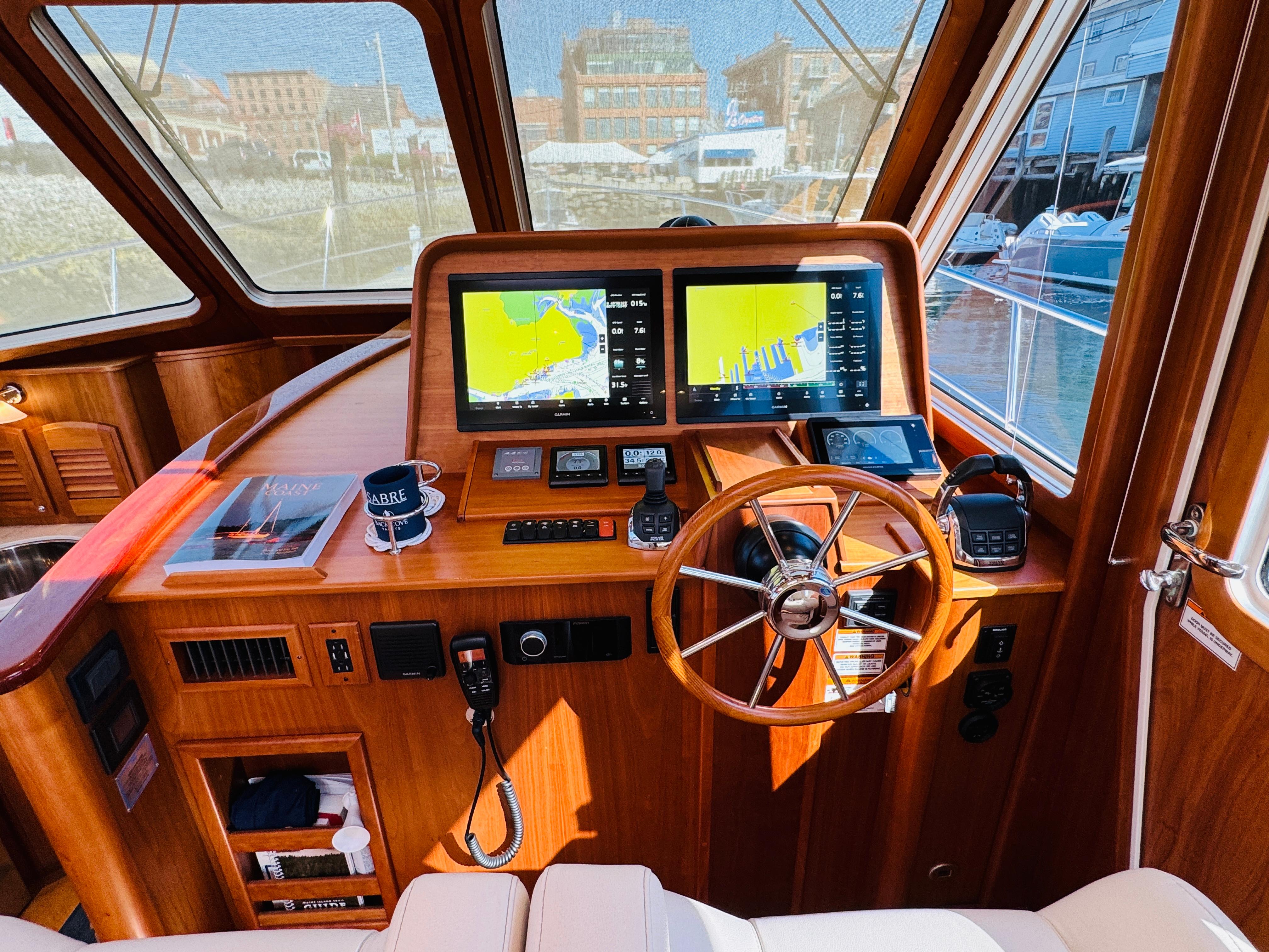 Helm of 2018 Sabre 42 Salon Express with navigation screens and wooden steering wheel.