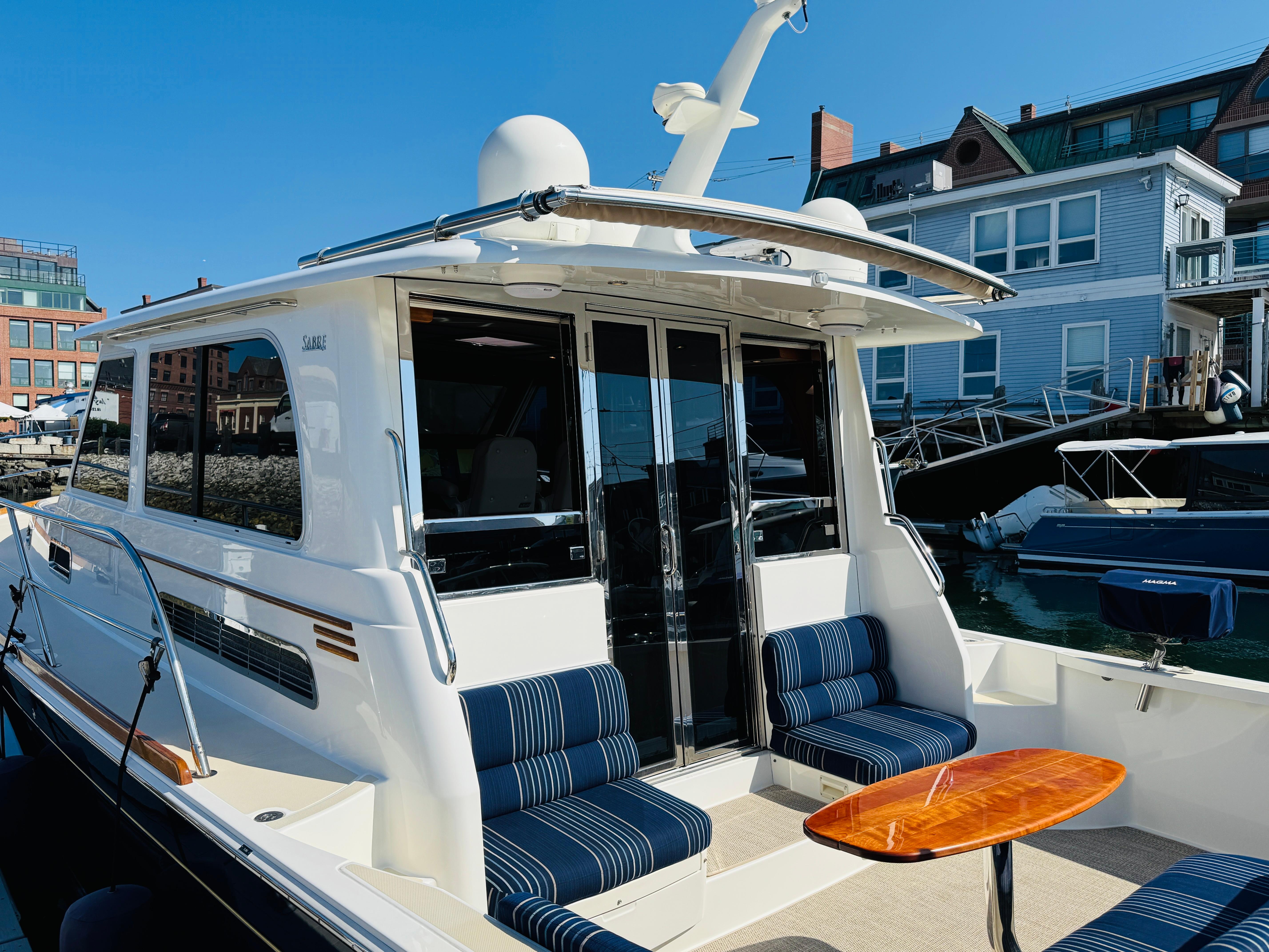 2018 Sabre 42 Salon Express yacht with striped seating and wooden table, docked at marina.