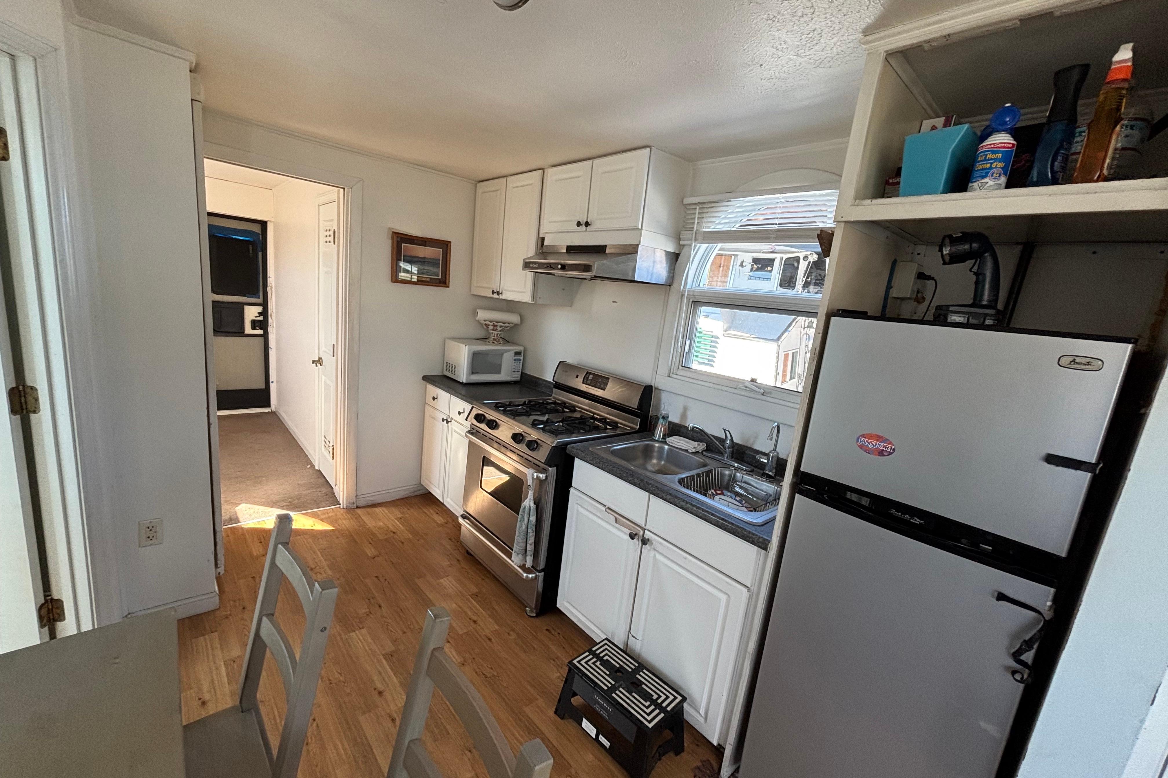 Compact kitchen in a 2004 River Floating Home with modern appliances and wooden flooring.