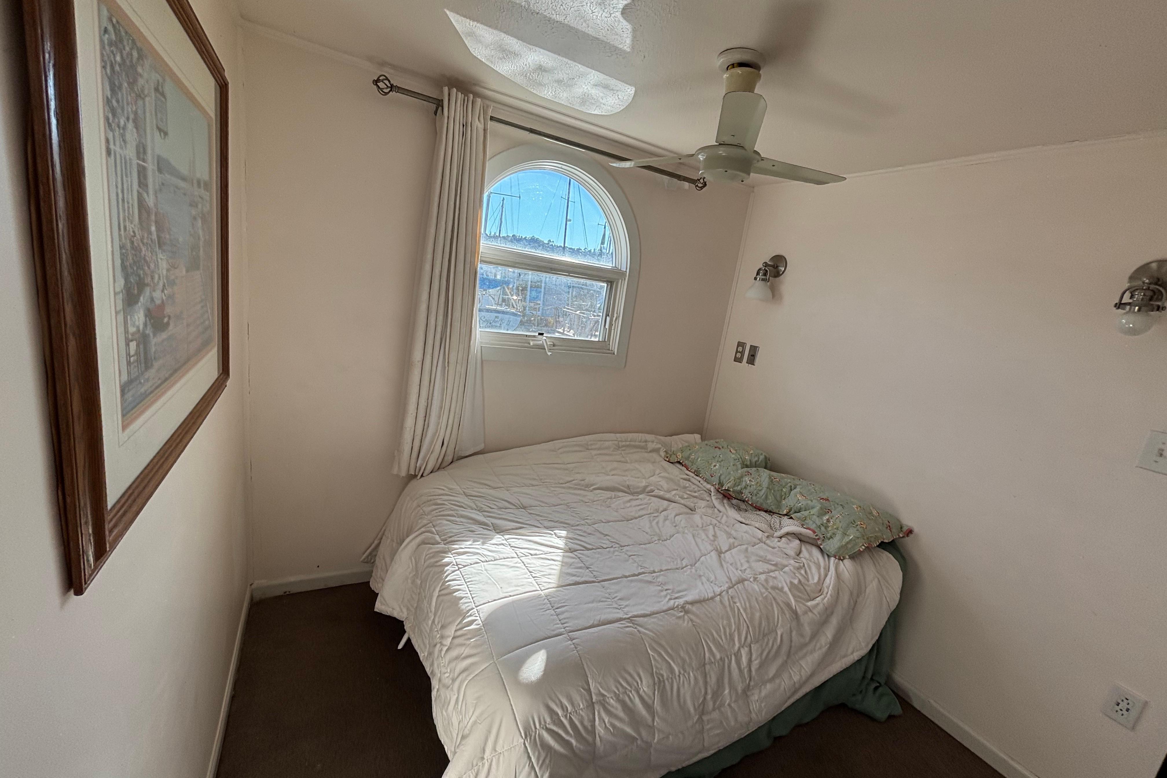 Cozy bedroom in 2004 River Floating Home with window, ceiling fan, and wall art.