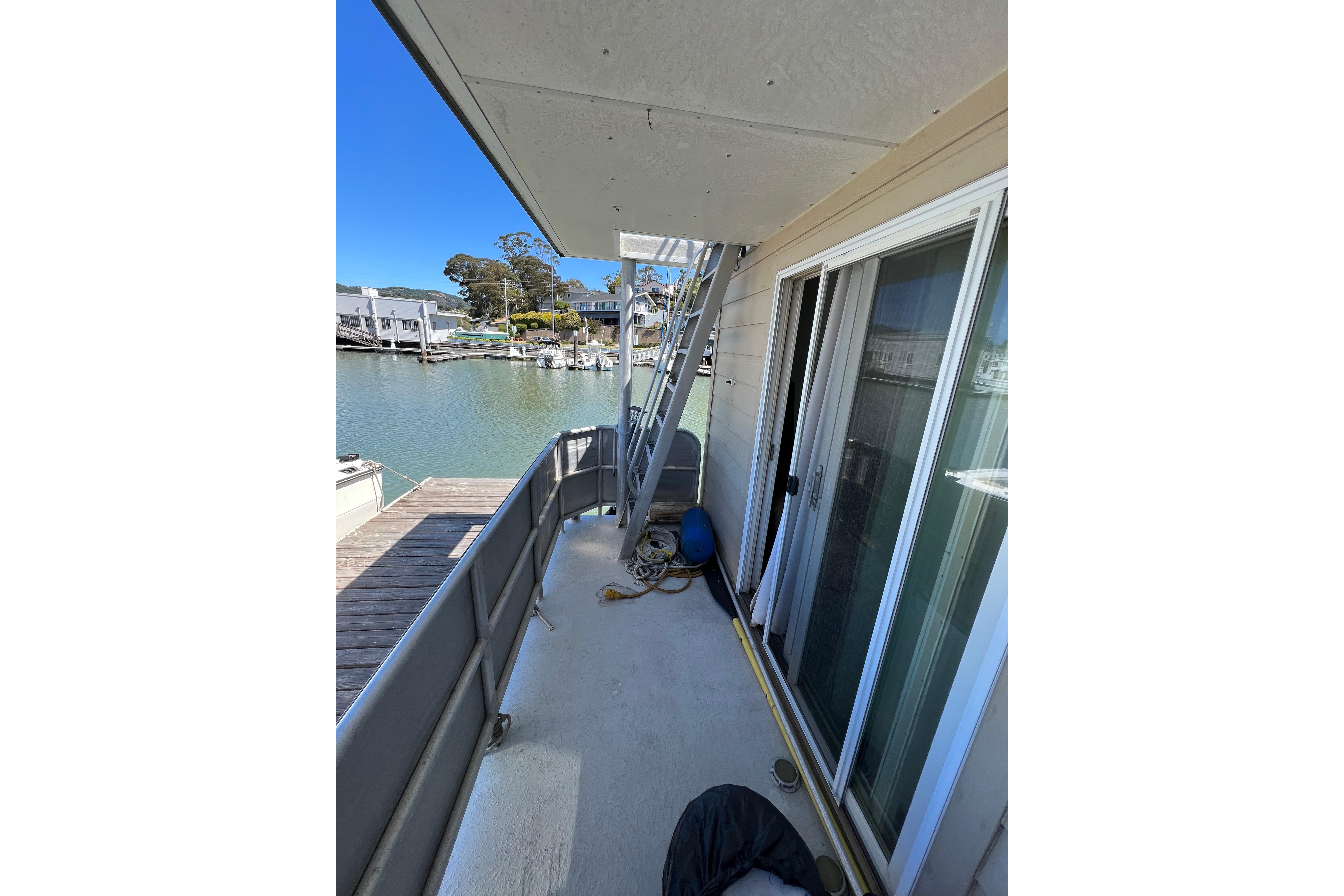 Floating home deck with sliding glass doors, overlooking a serene waterfront view.