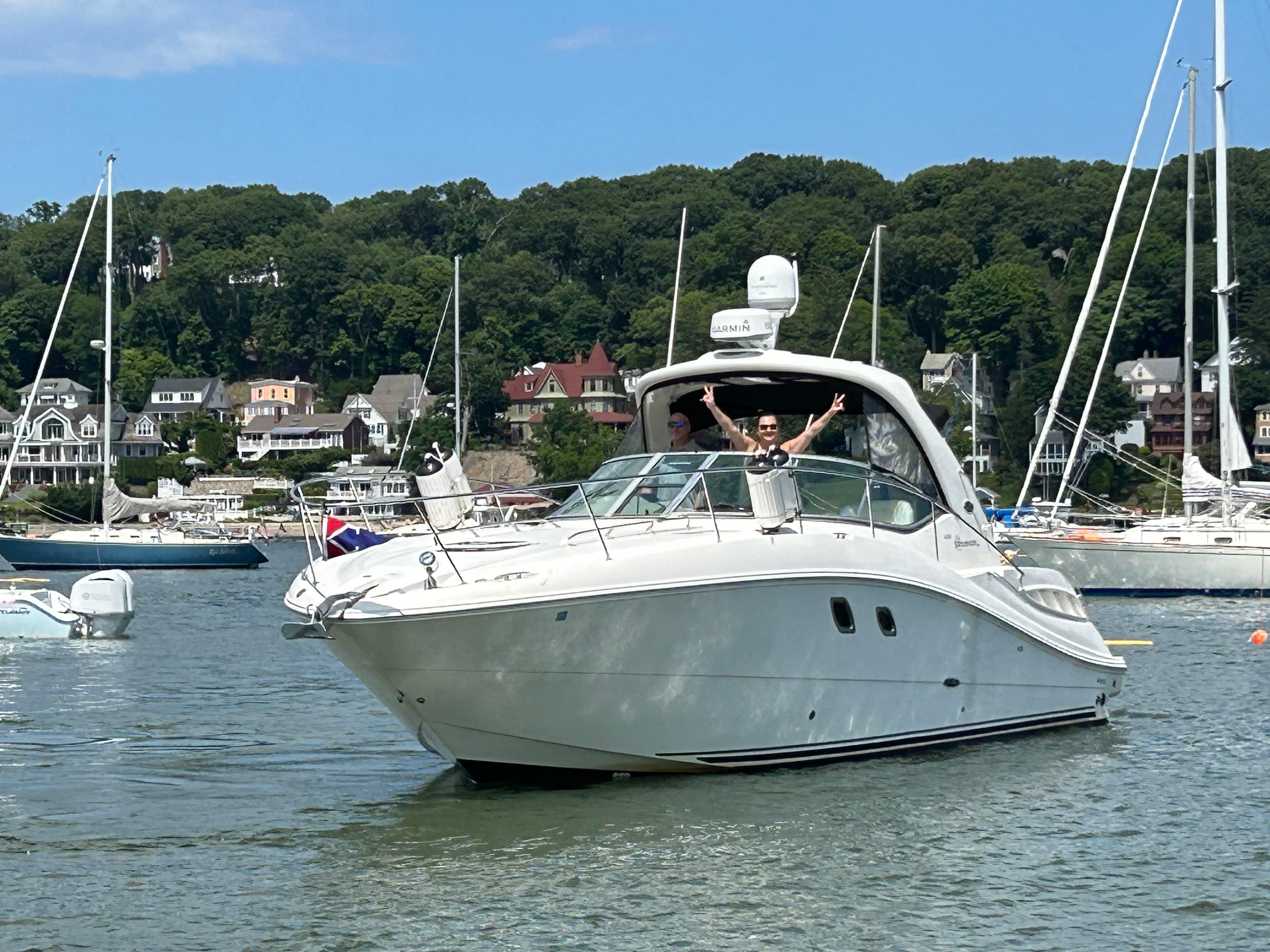 2008 Sea Ray 330 Sundancer yacht cruising in a scenic harbor with lush greenery.