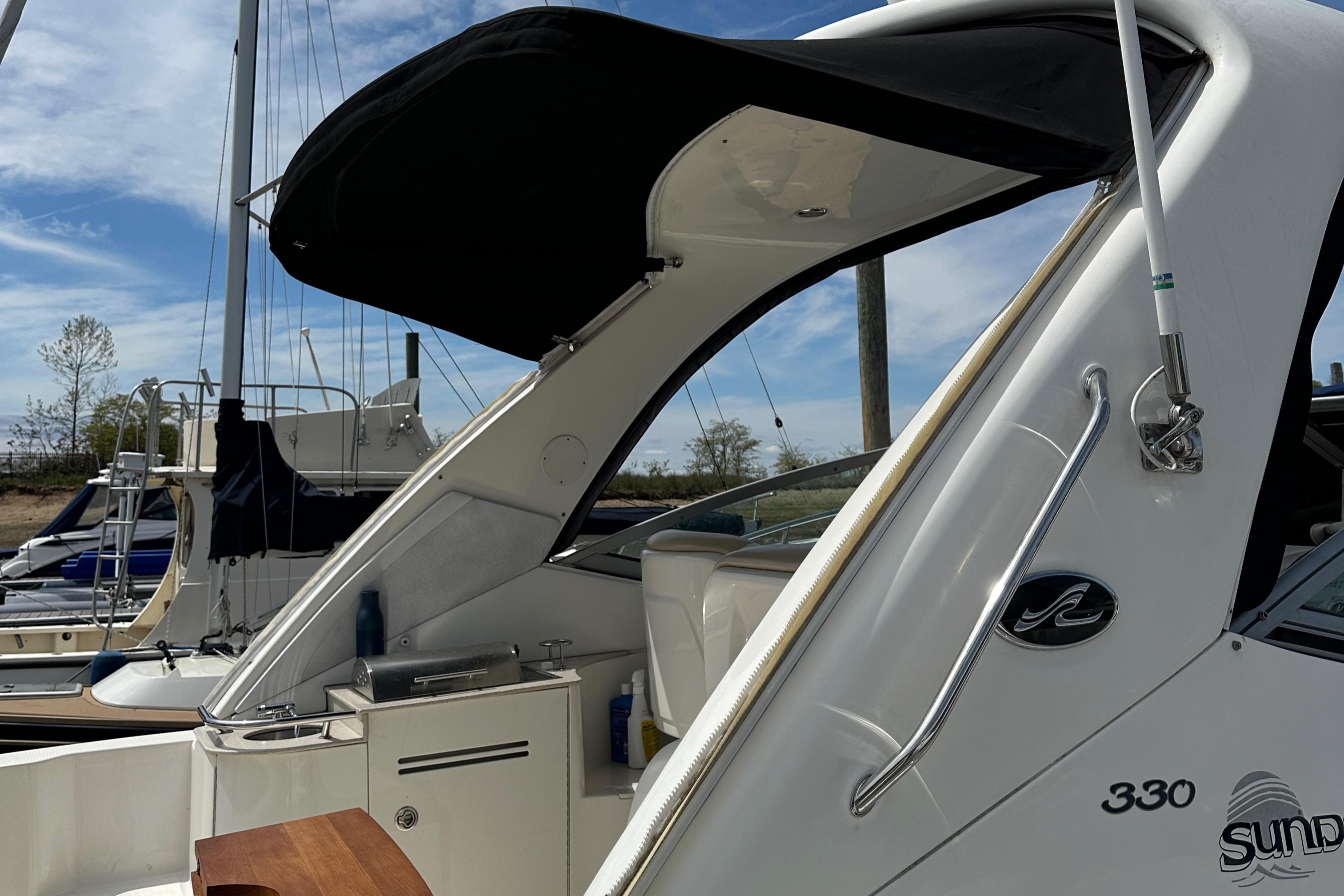 2008 Sea Ray 330 Sundancer yacht with black canopy, docked at marina.