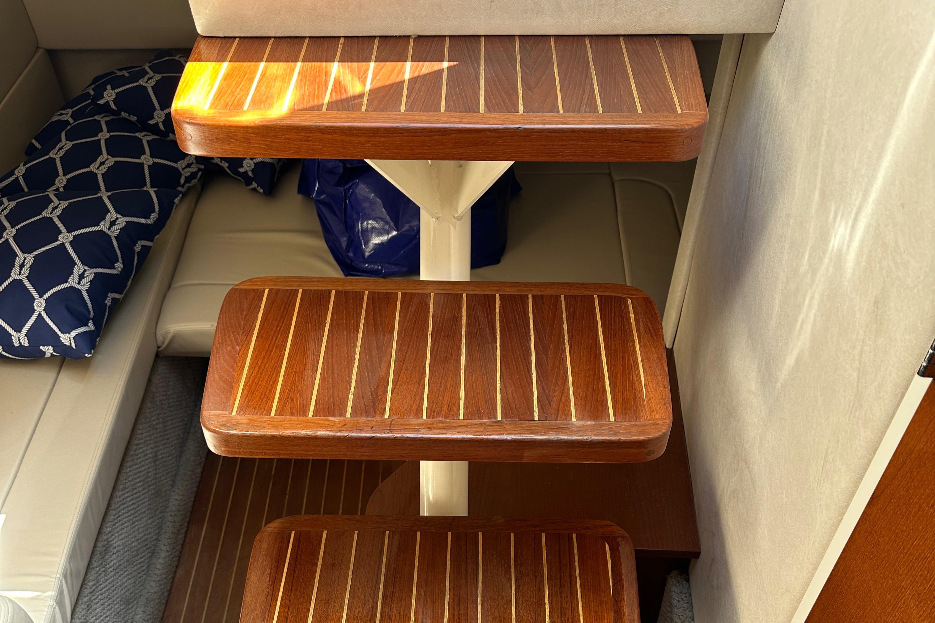 Wooden steps inside 2008 Sea Ray 330 Sundancer yacht, with nautical-themed cushion.