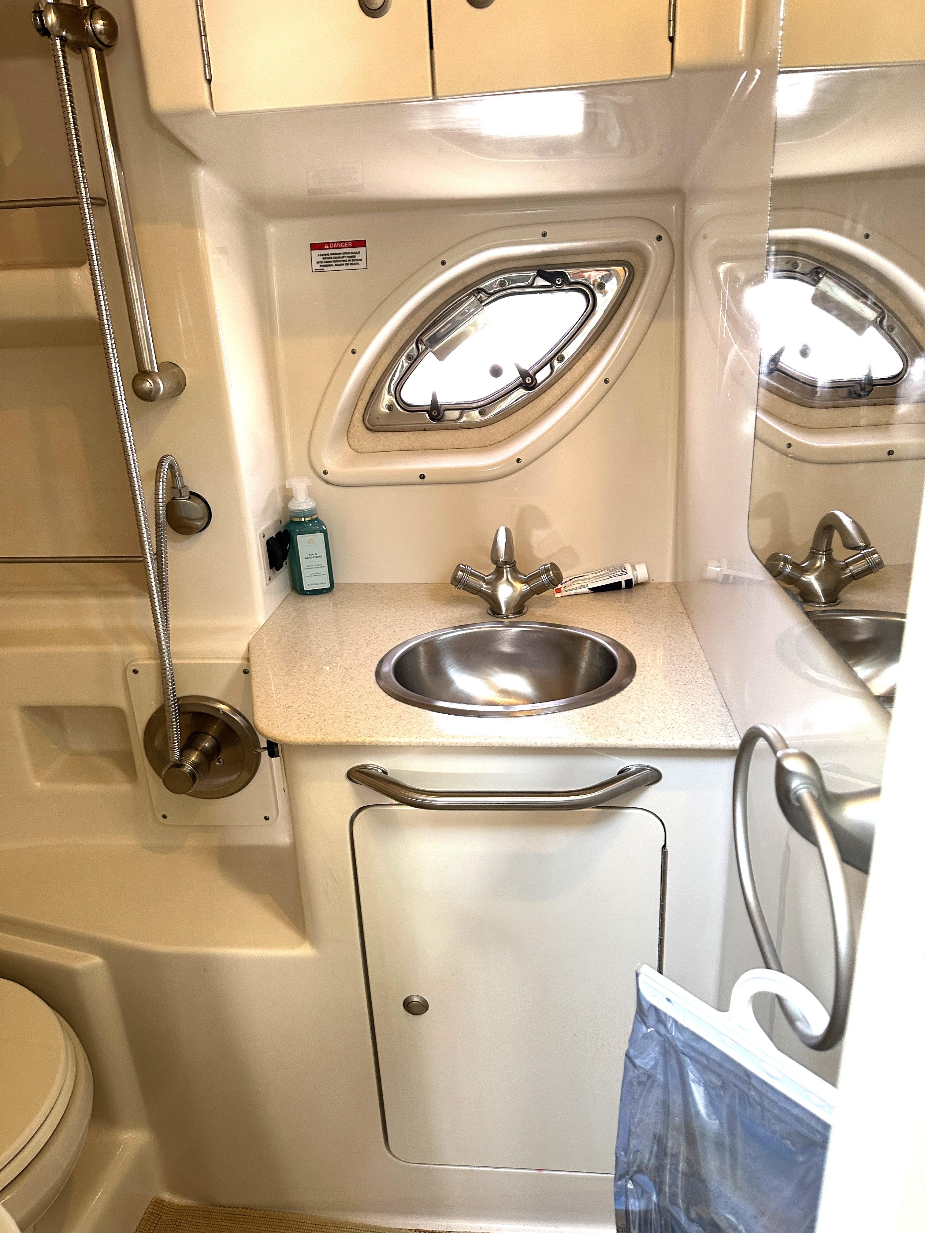 2008 Sea Ray 330 Sundancer bathroom with sink, mirror, and porthole window.