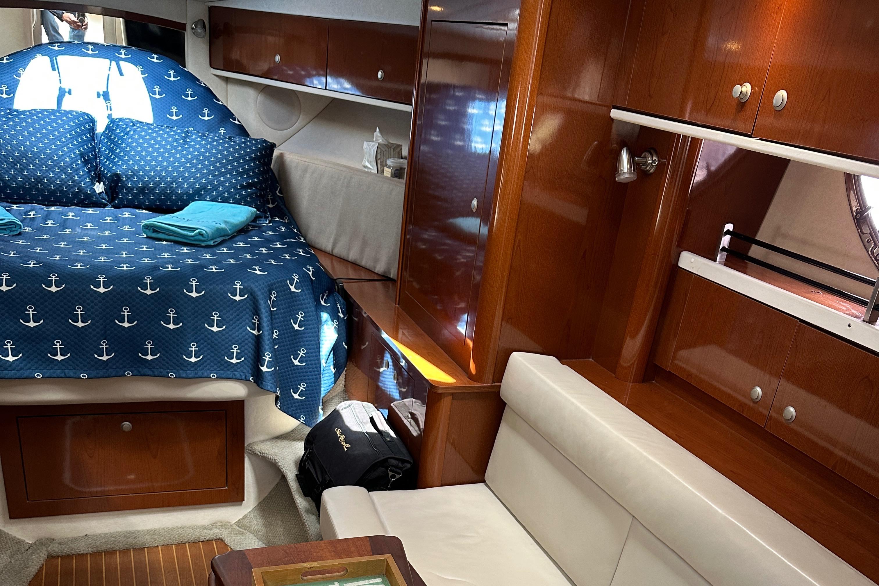 Interior of 2008 Sea Ray 330 Sundancer with cozy bed and wooden cabinetry.