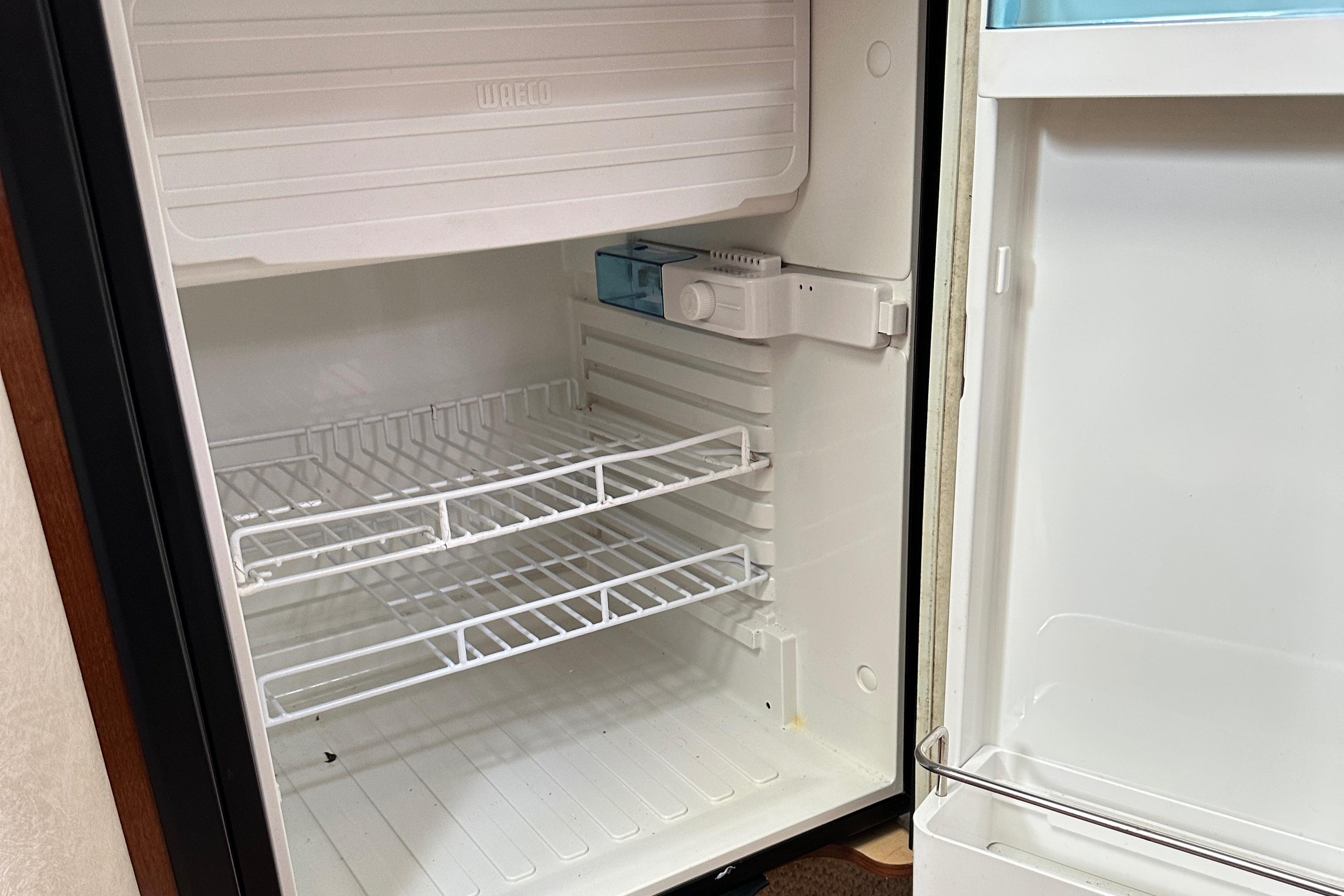 Empty refrigerator inside a 2008 Sea Ray 330 Sundancer boat, featuring wire shelves.