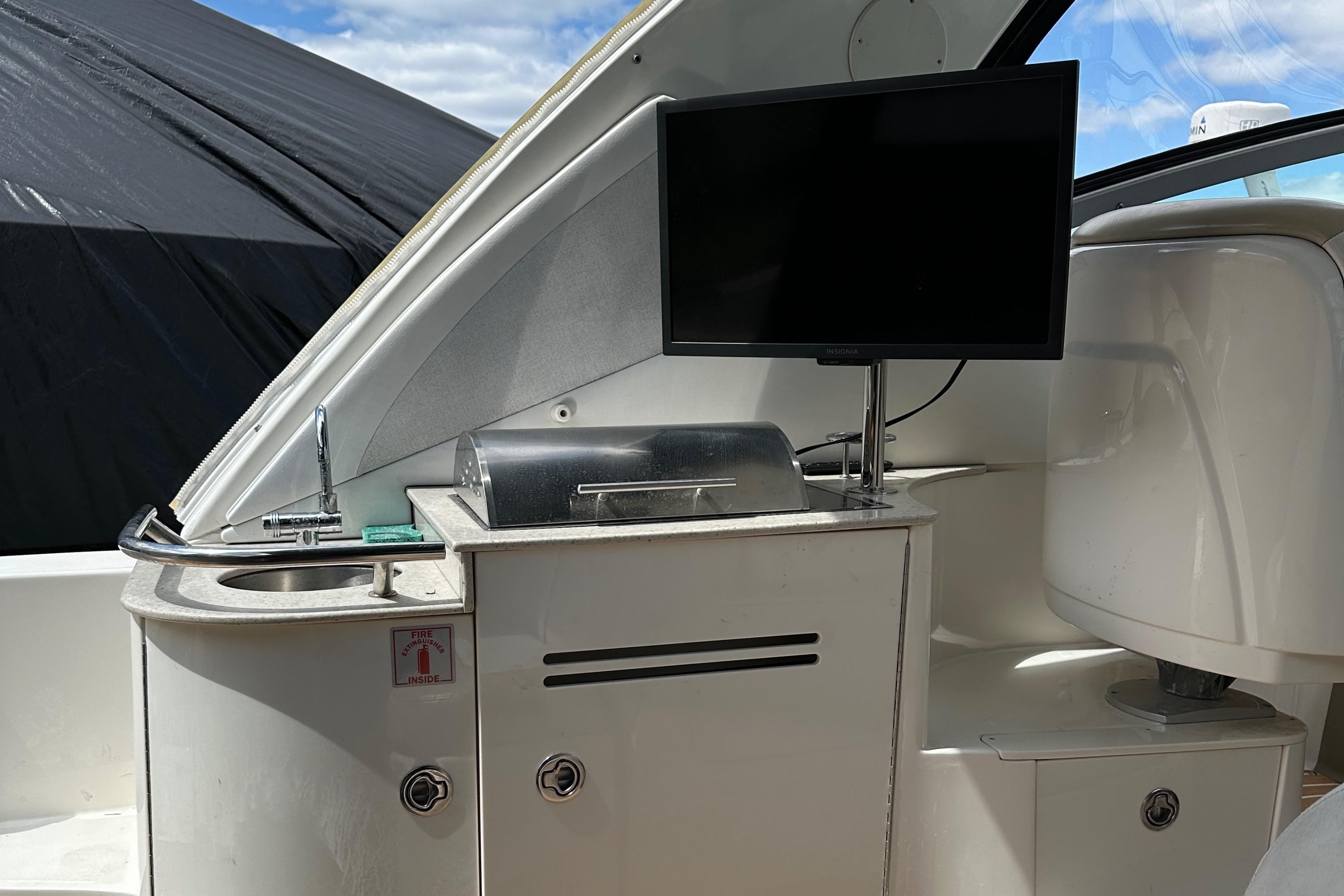 2008 Sea Ray 330 Sundancer boat interior with sink, grill, and mounted TV.