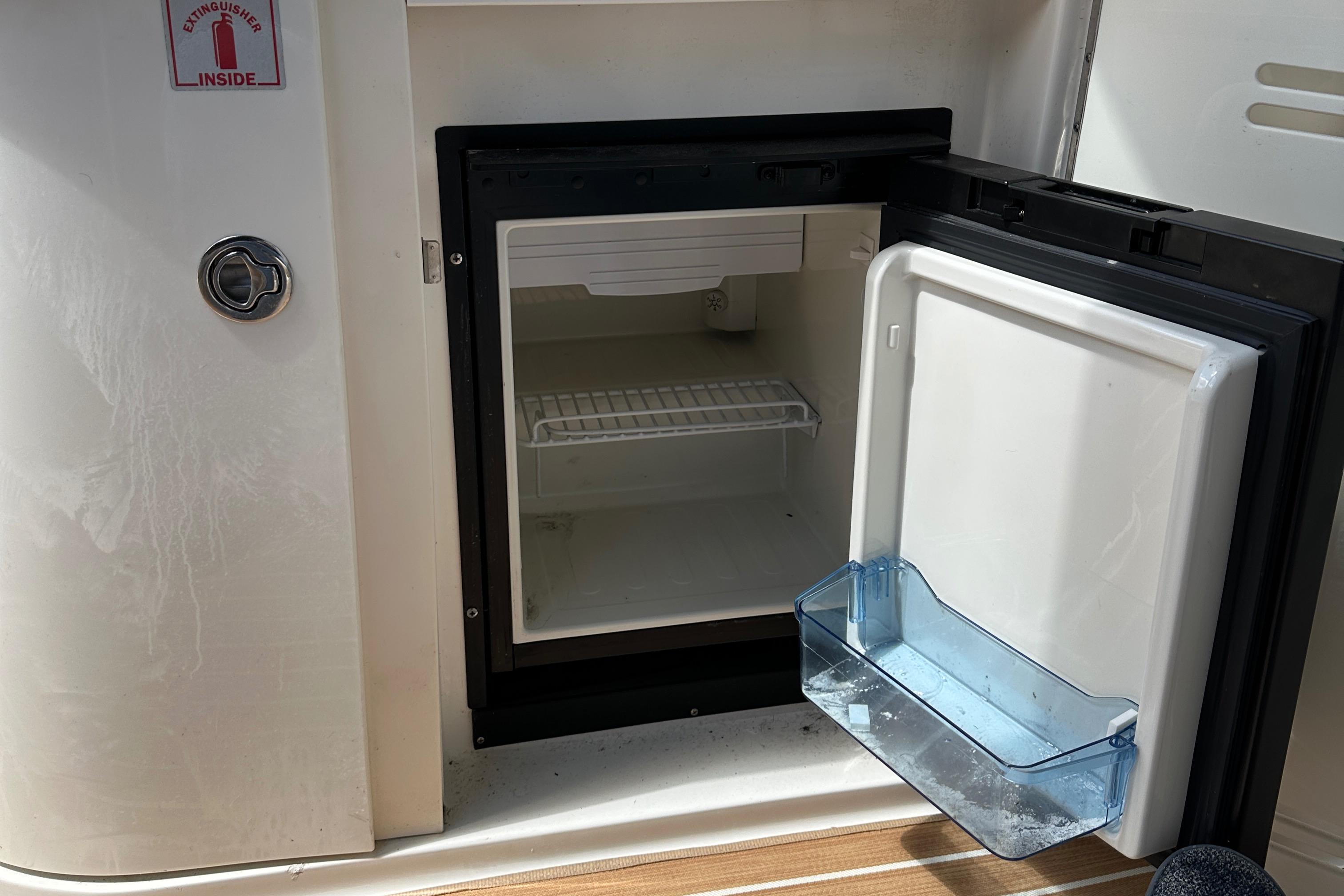 Open mini fridge on 2008 Sea Ray 330 Sundancer boat, showing interior shelving.