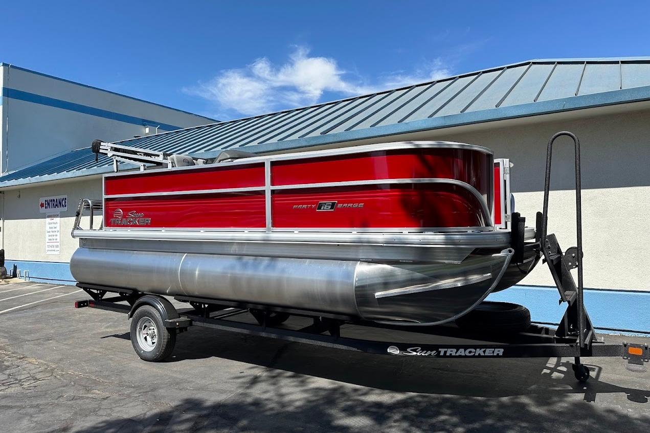 2026 Sun Tracker Party Barge 18 DLX pontoon boat on trailer, parked outdoors.