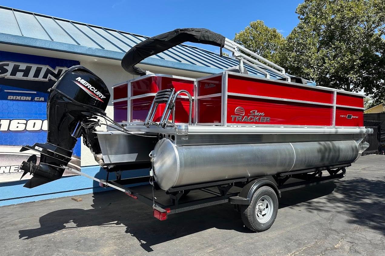 2026 Sun Tracker Party Barge 18 DLX pontoon boat with Mercury engine, parked outdoors.