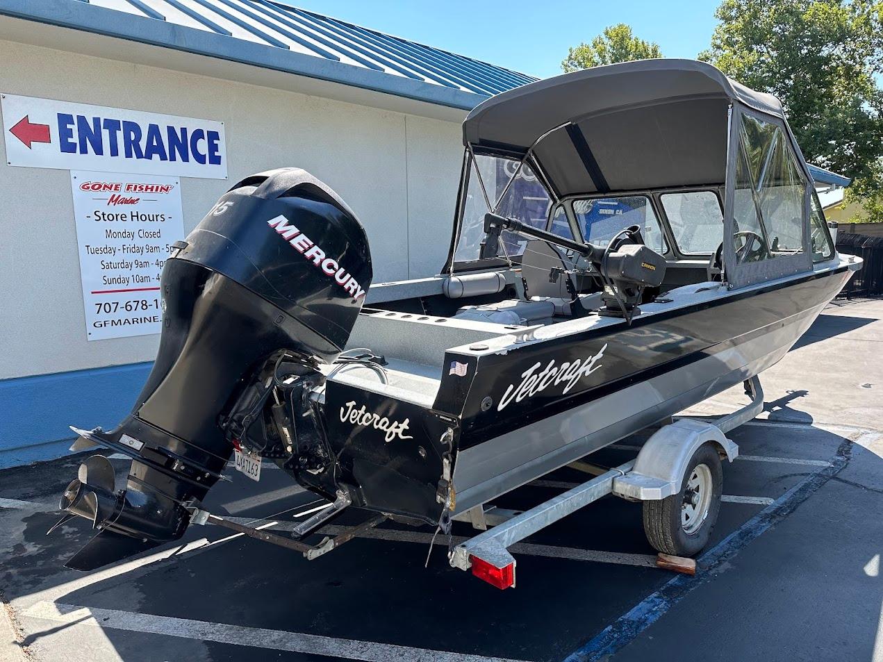 2008 Jetcraft 1925 Adventurer boat with Mercury engine on trailer, parked outside store.