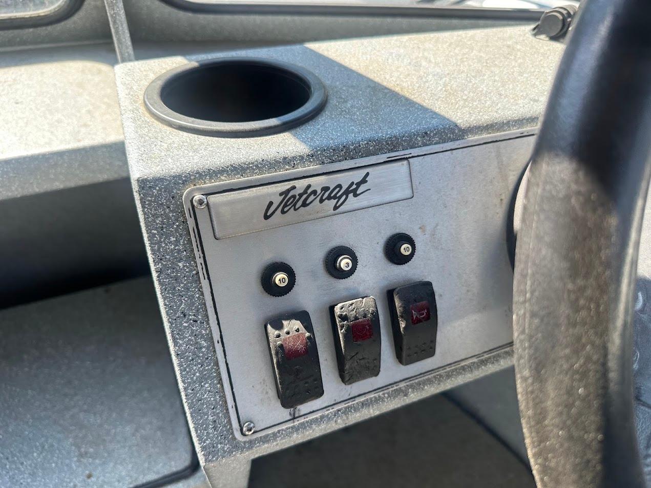 Control panel of a 2008 Jetcraft 1925 Adventurer boat with switches and cup holder.