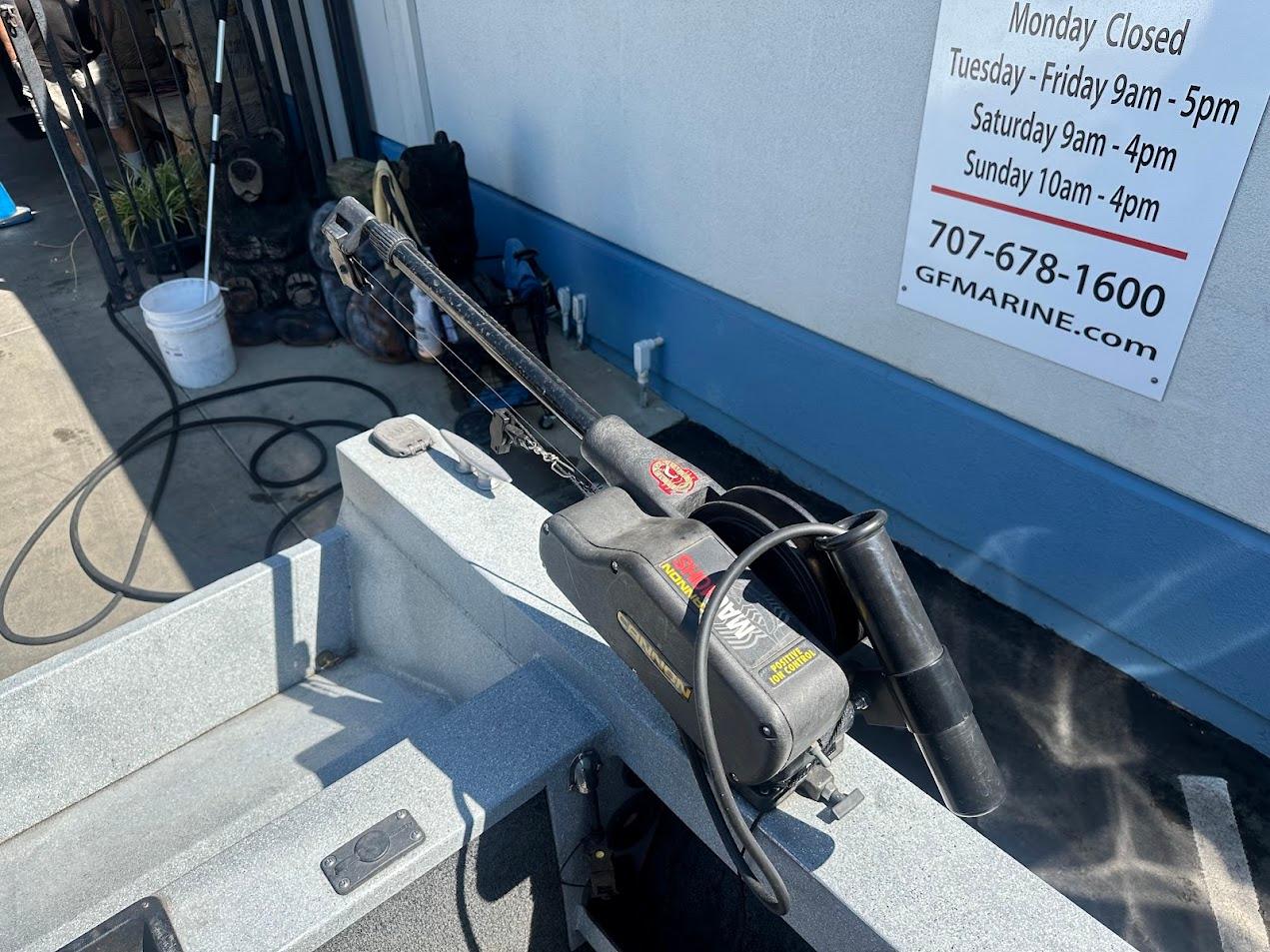 Jetcraft 1925 Adventurer boat detail with fishing equipment, parked near a marine service shop.
