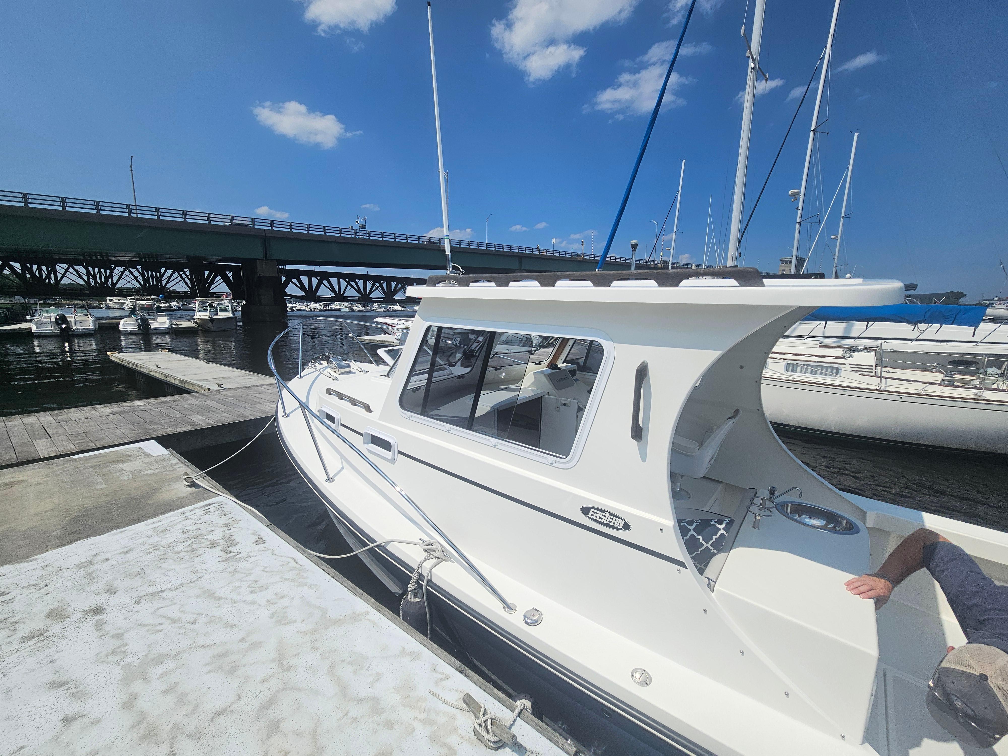 2019 Eastern 248 Explorer boat docked by a bridge on a sunny day.