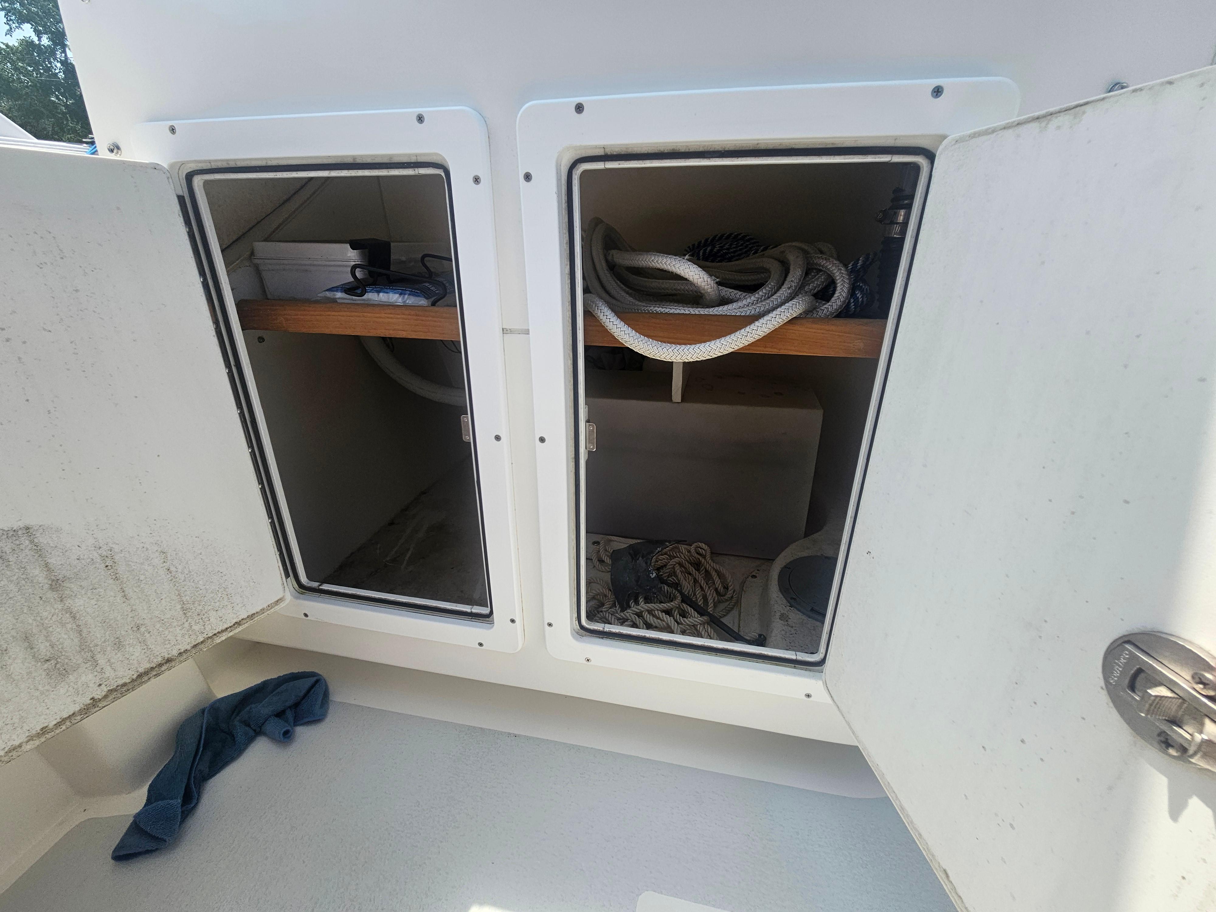 Open storage compartments on a 2019 Eastern 248 Explorer boat, containing ropes and equipment.