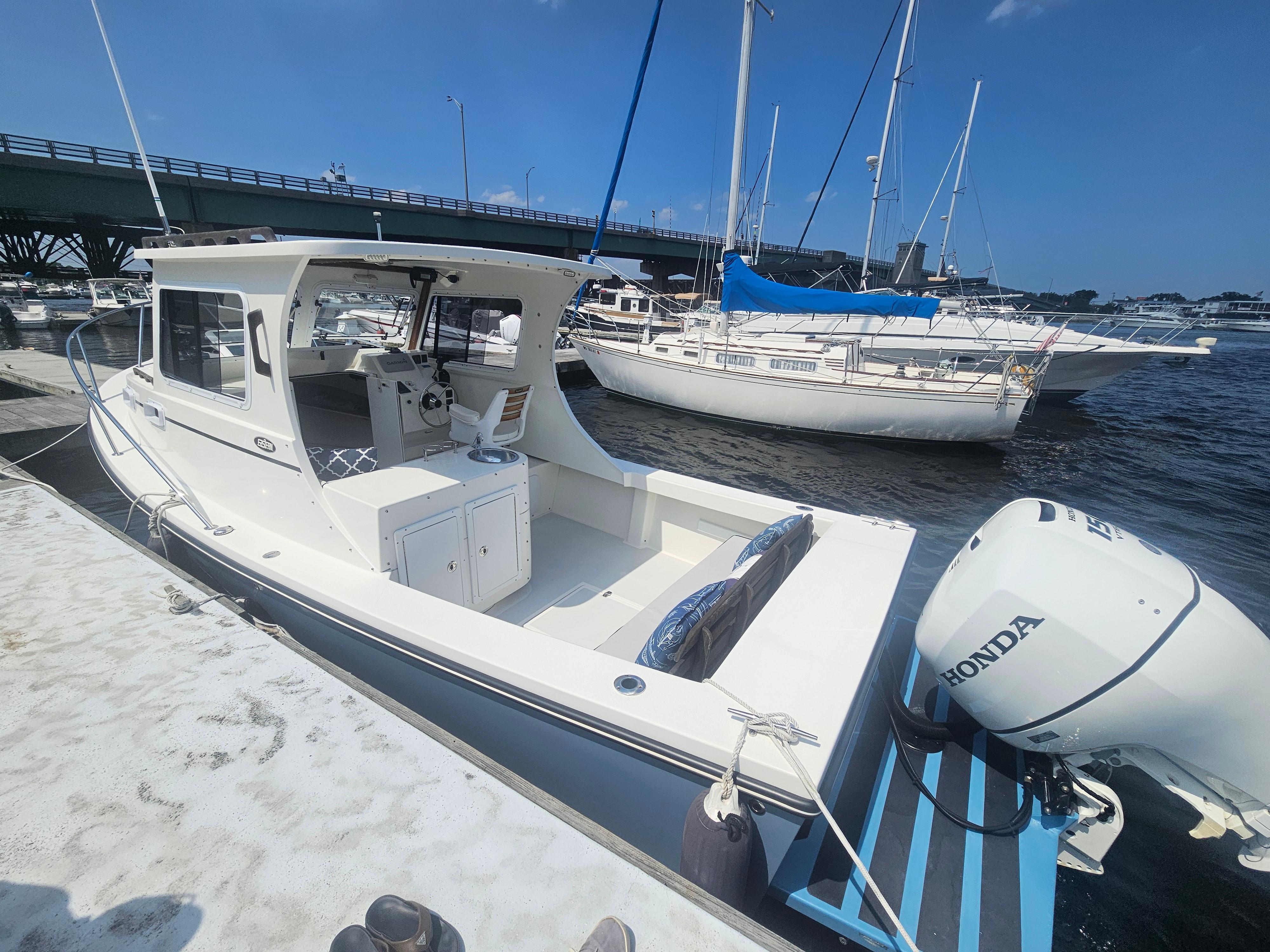 2019 Eastern 248 Explorer boat docked, featuring a Honda outboard motor, under a clear blue sky.