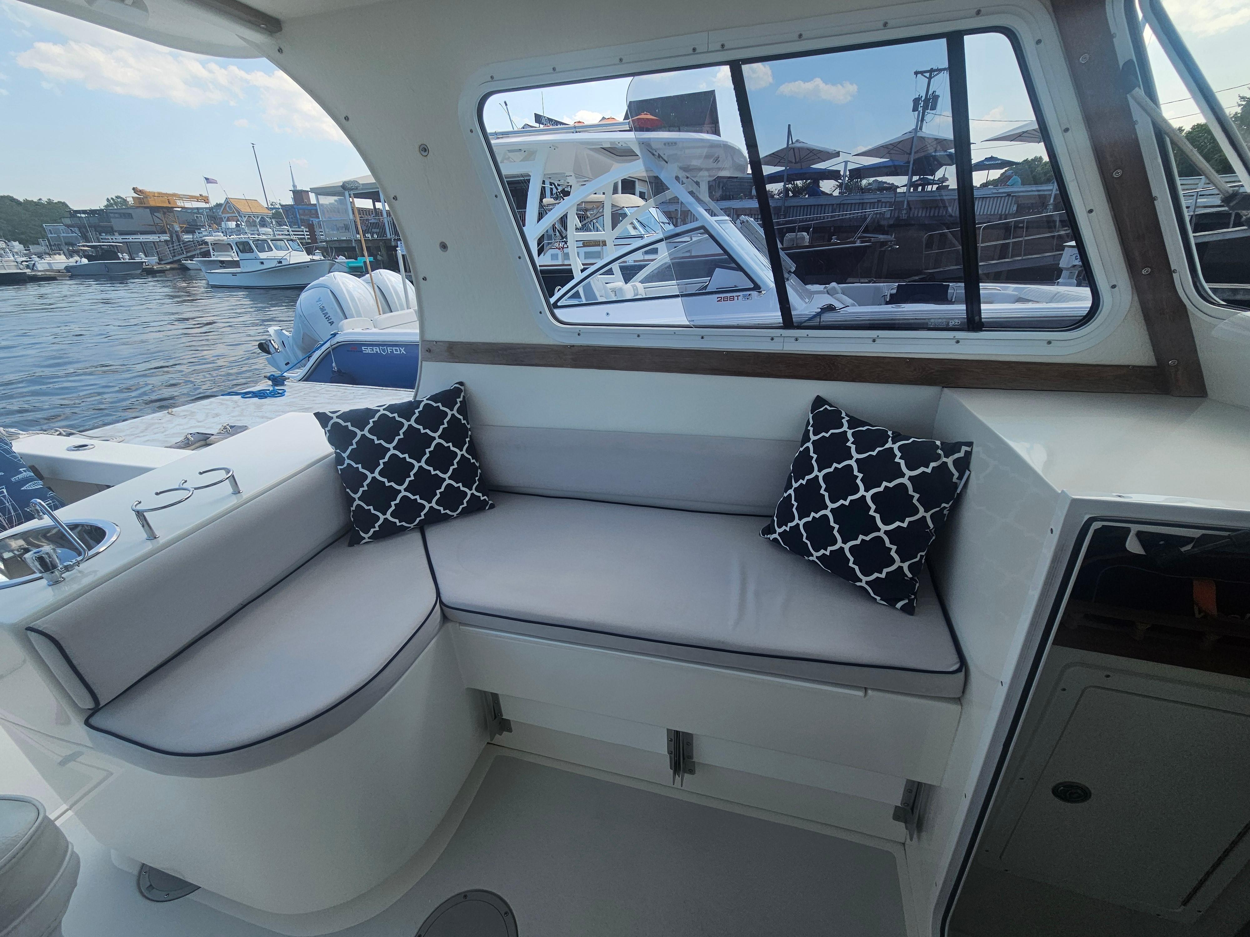 Interior of 2019 Eastern 248 Explorer boat with cushioned seating and decorative pillows.