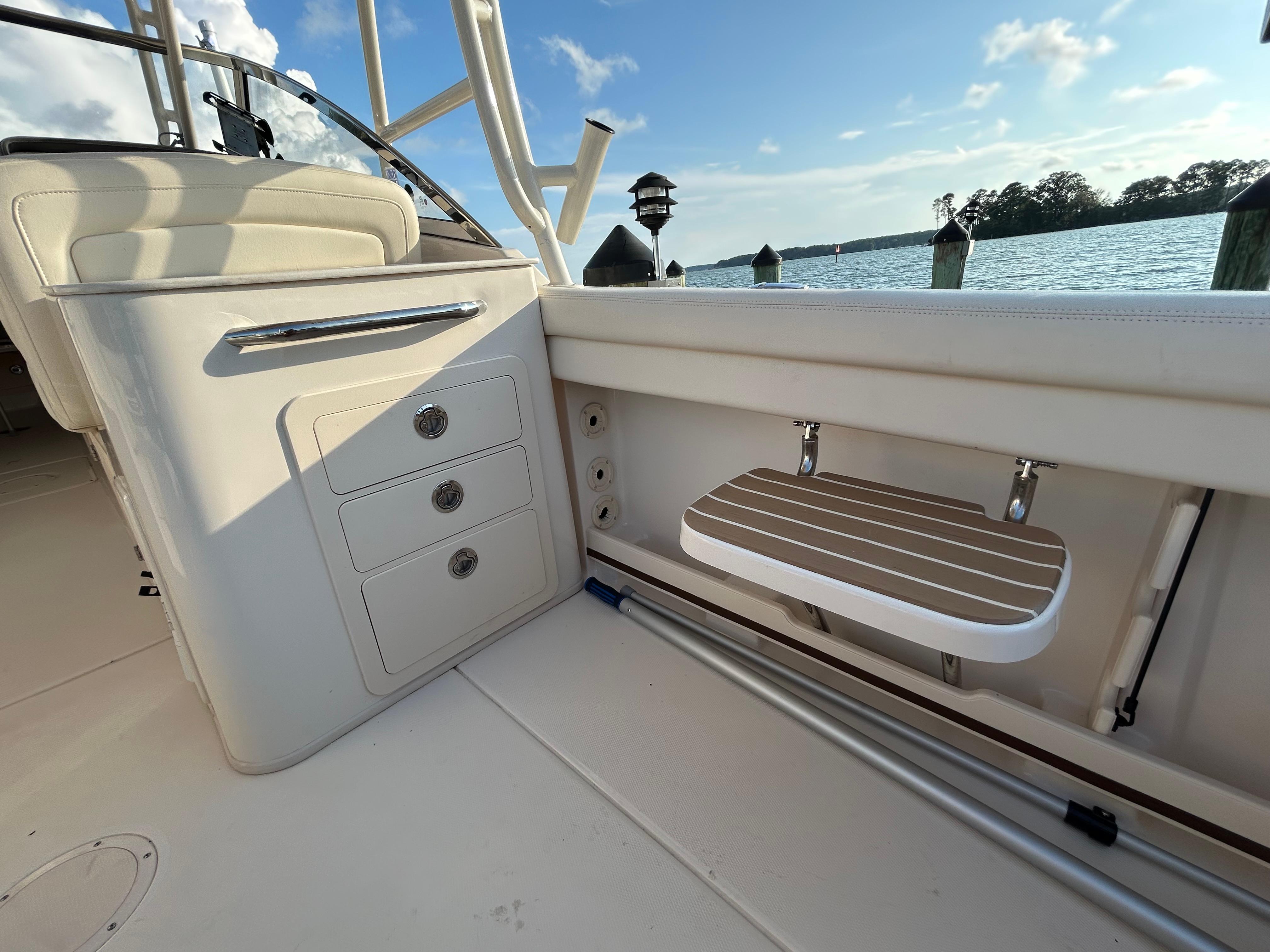 2023 Grady-White Freedom 275 boat interior with storage drawers and foldable seat by the water.