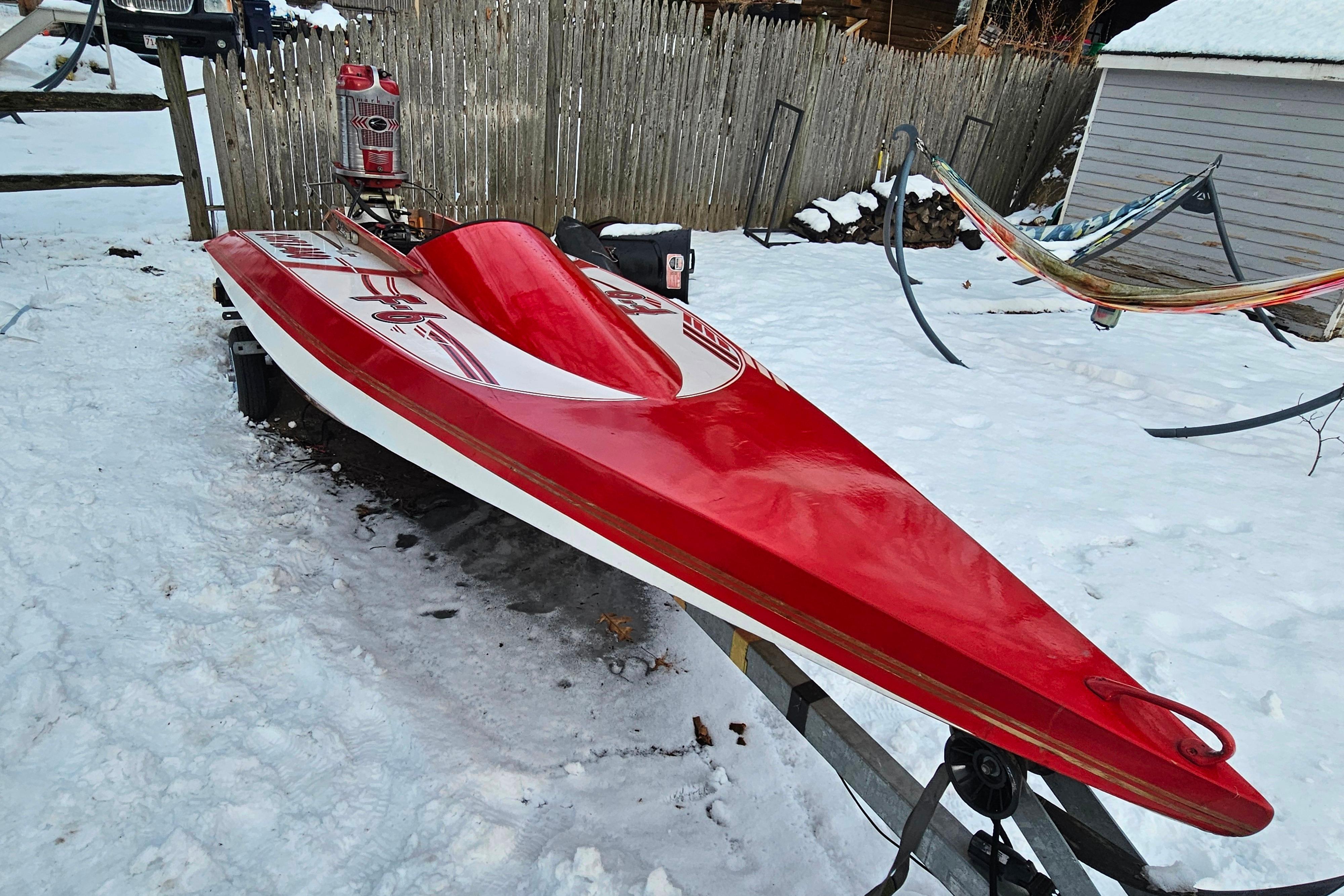 1987 De Silva F Class Race boat in snow, vibrant red hull, on trailer.
