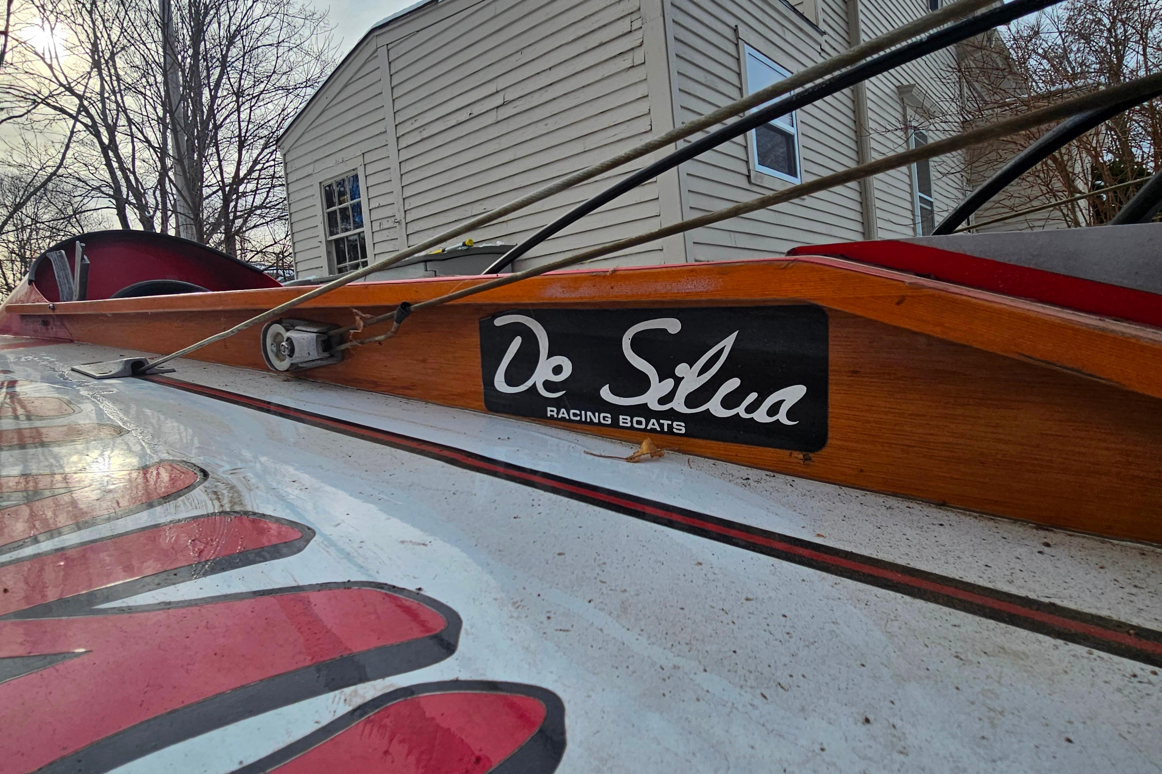 1987 De Silva F Class Race boat with wooden detailing and logo, parked near a house.
