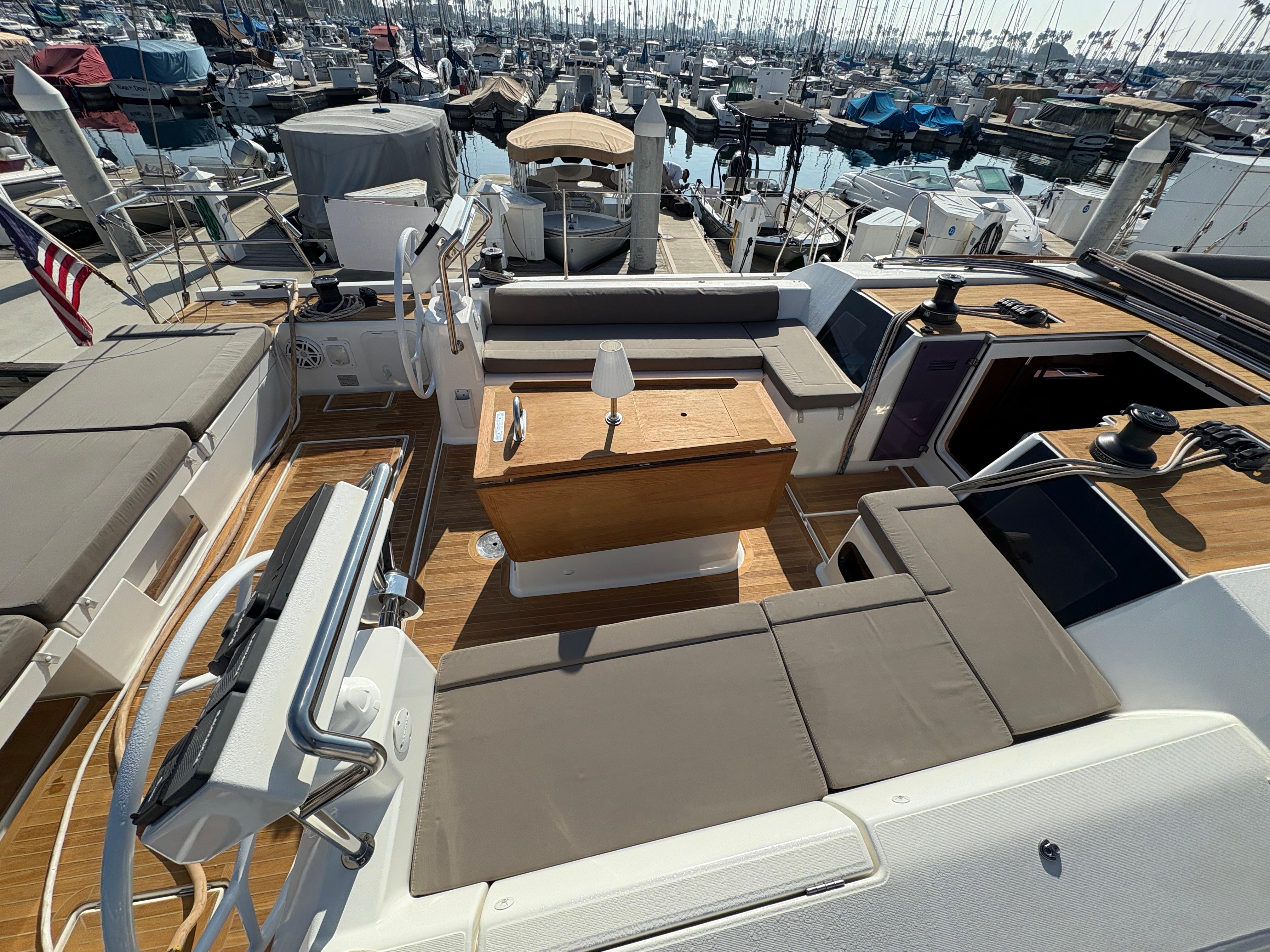 Dufour-560 Exclusive 2018-560 Exclusive US-2018 Dufour 560 Exclusive yacht deck with seating and table, docked in a marina.-9765971 | Thumbnail