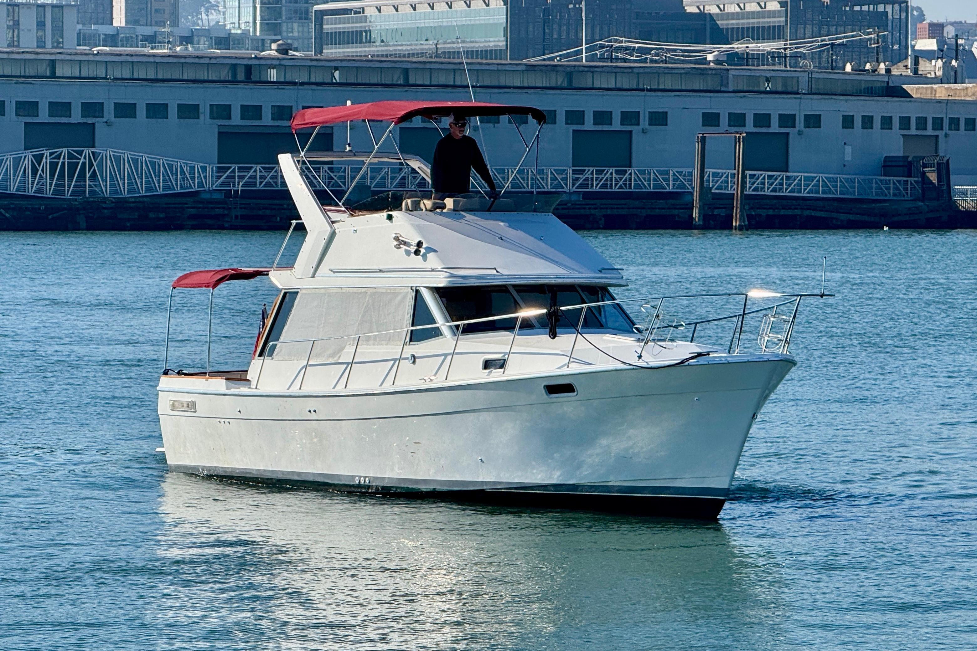 1989 Bayliner 3288 Motoryacht cruising in a harbor with red canopy.