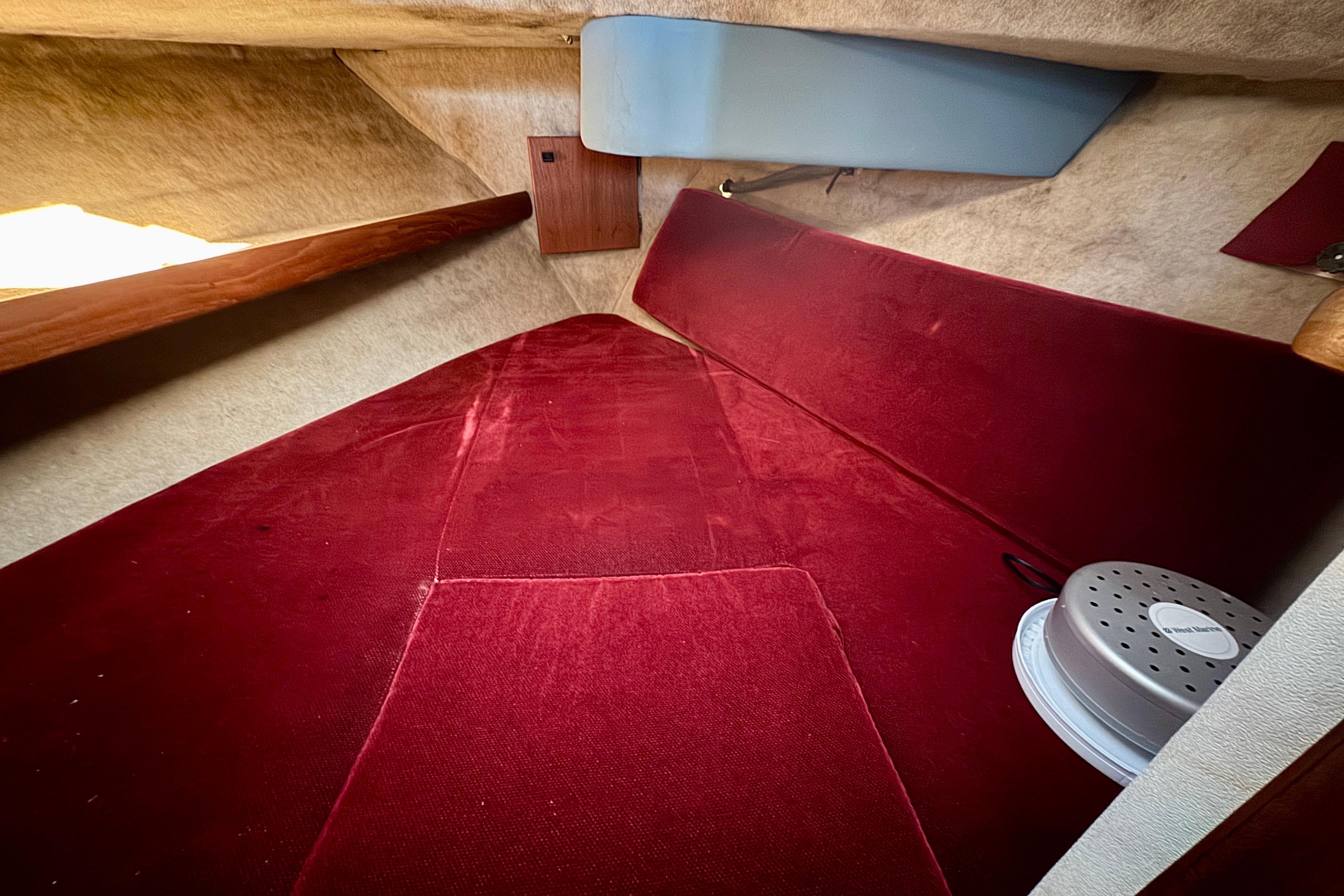 Interior cabin of 1989 Bayliner 3288 Motoryacht with red upholstery and storage space.