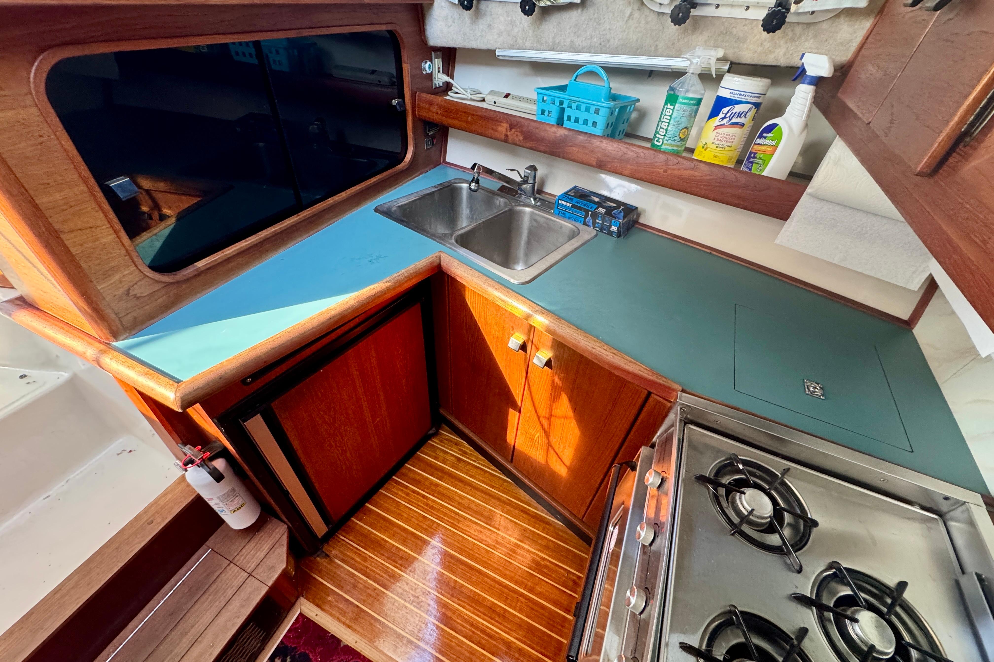 1989 Bayliner 3288 Motoryacht kitchen with stove, sink, and cleaning supplies.
