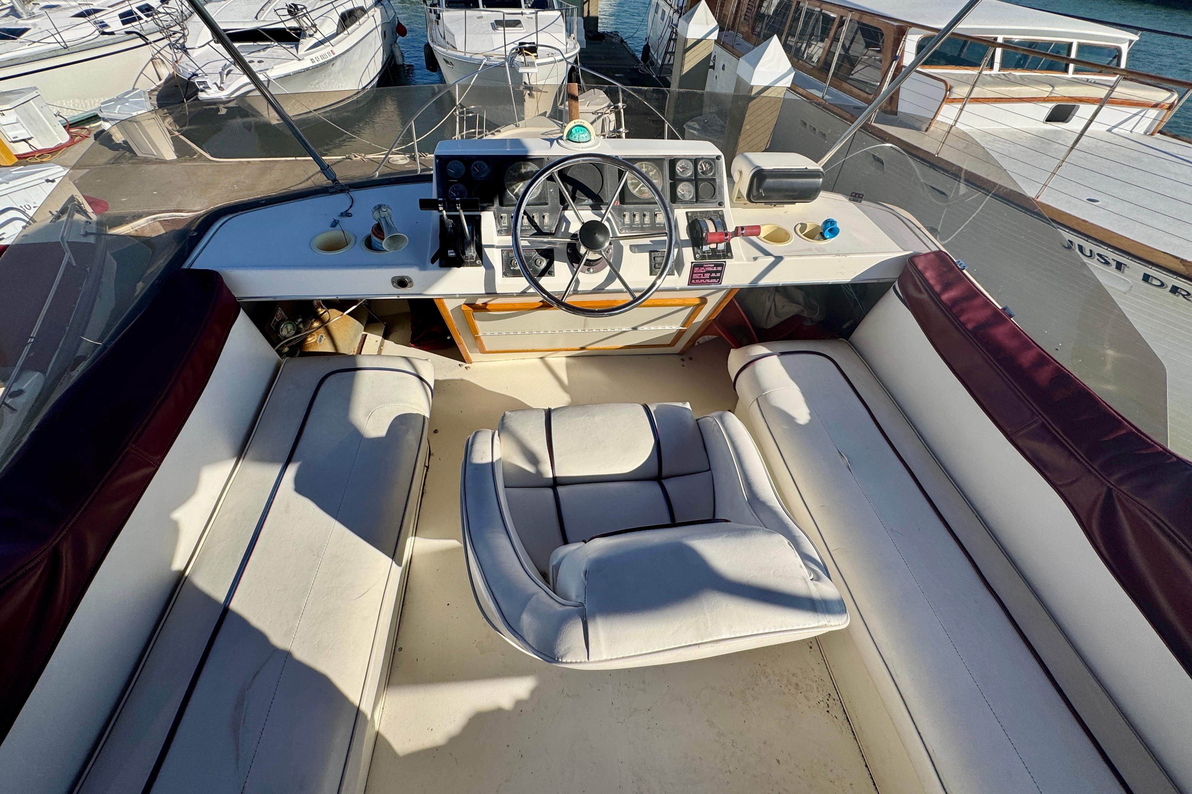 1989 Bayliner 3288 Motoryacht cockpit with steering wheel and seating, docked at marina.