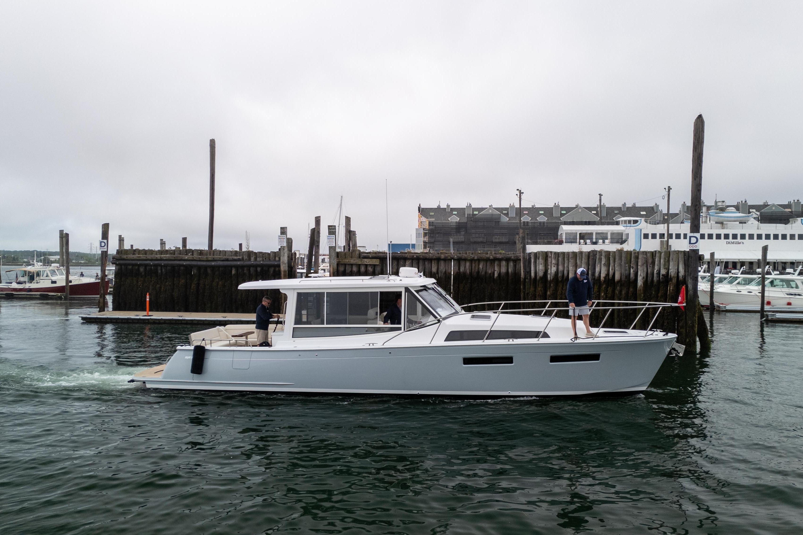 2026 MJM 47 R yacht cruising near a marina with overcast skies.