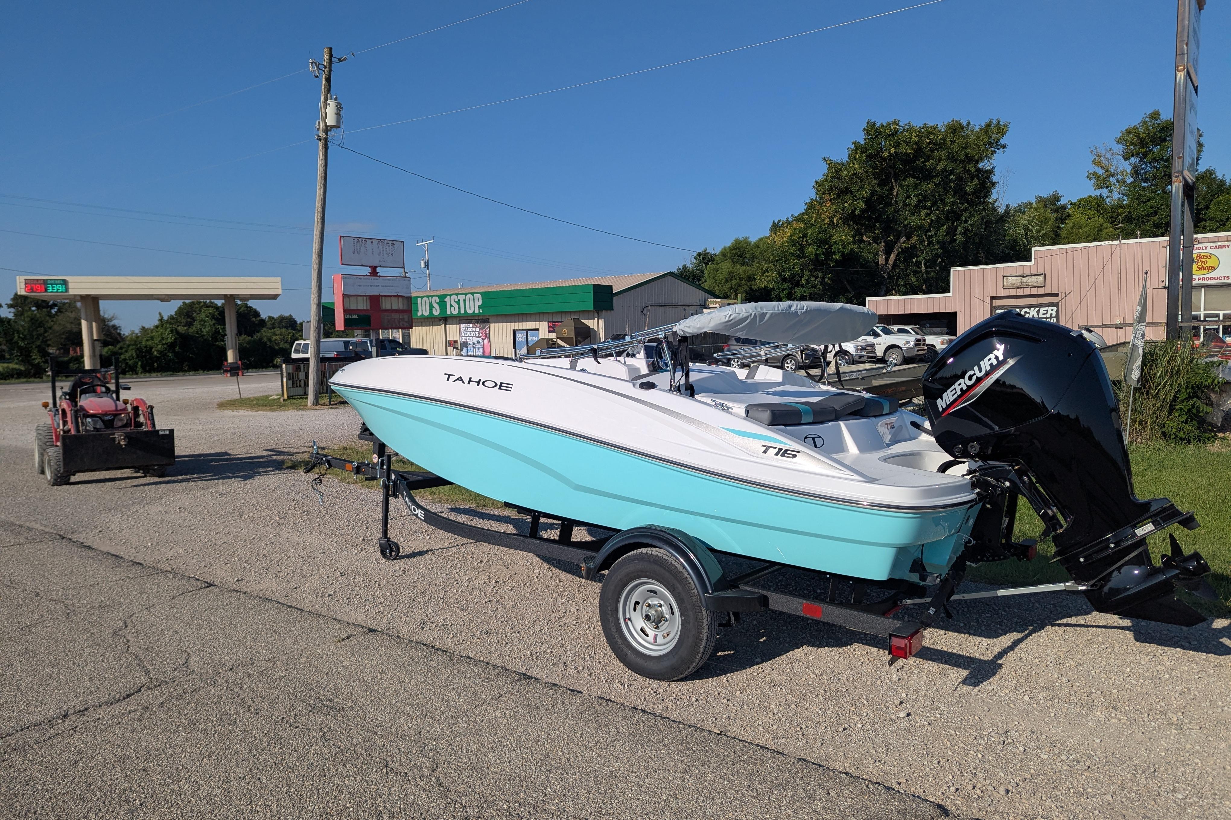 2026 Tahoe T16 boat on trailer, parked near a rural gas station.