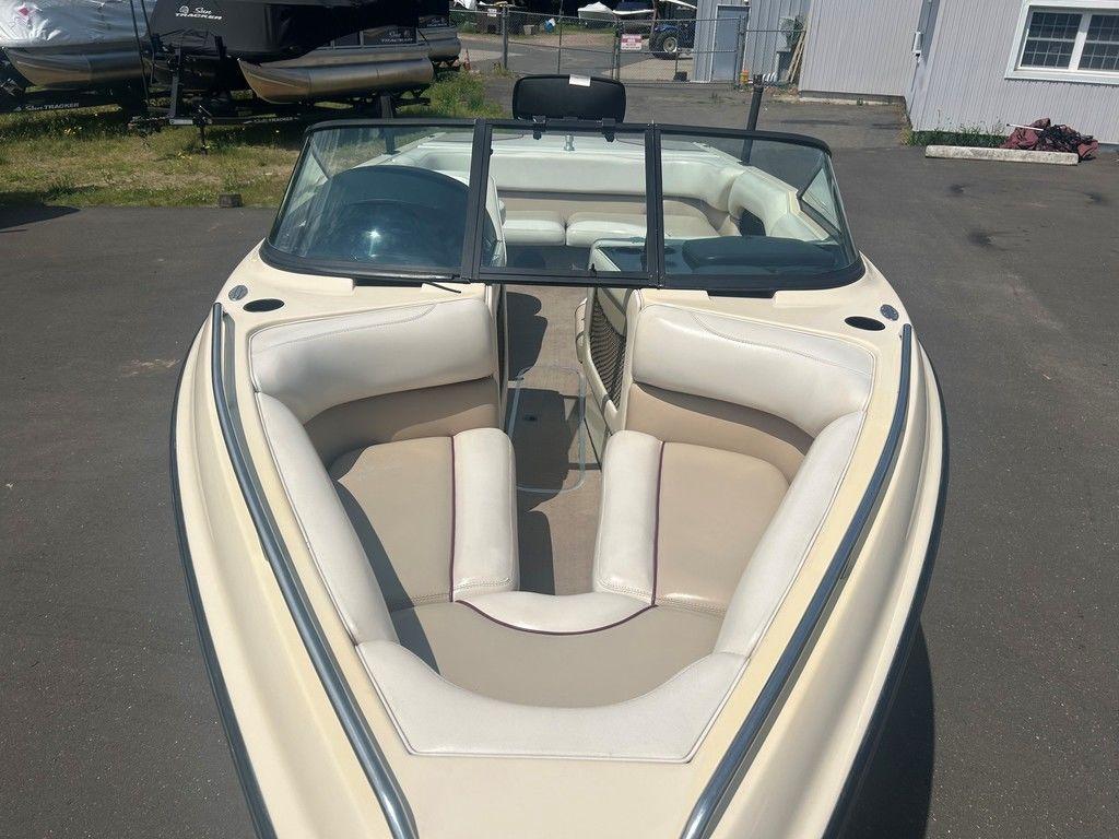 1999 Malibu Sunsetter VLX boat with beige interior, parked outdoors.