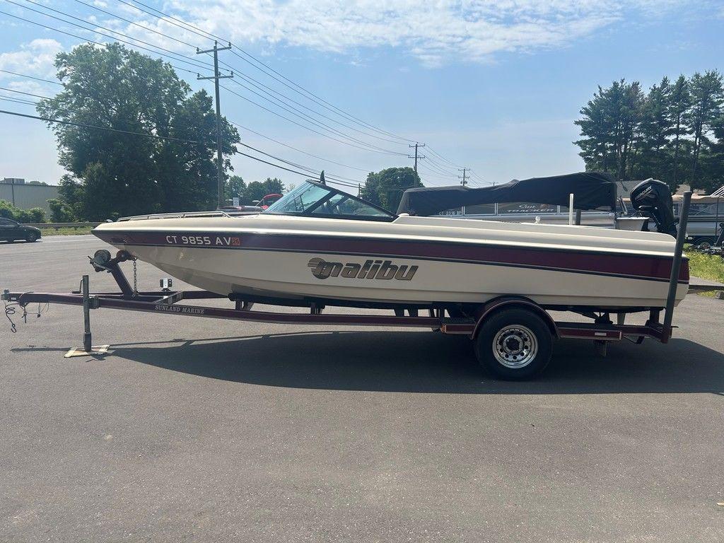 1999 Malibu Sunsetter VLX boat on trailer in sunny parking lot.