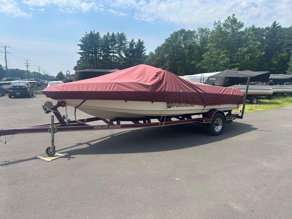 1999 Malibu Sunsetter VLX boat on trailer, covered with a red tarp, parked outdoors.