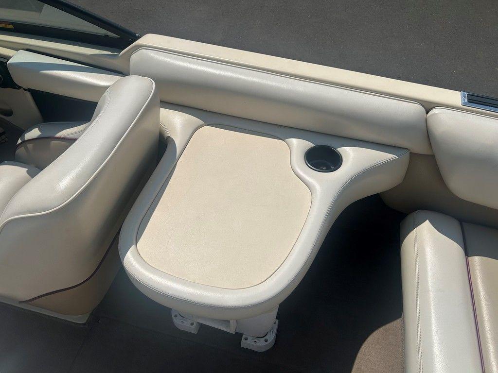 1999 Malibu Sunsetter VLX boat interior with beige seating and built-in cup holder.
