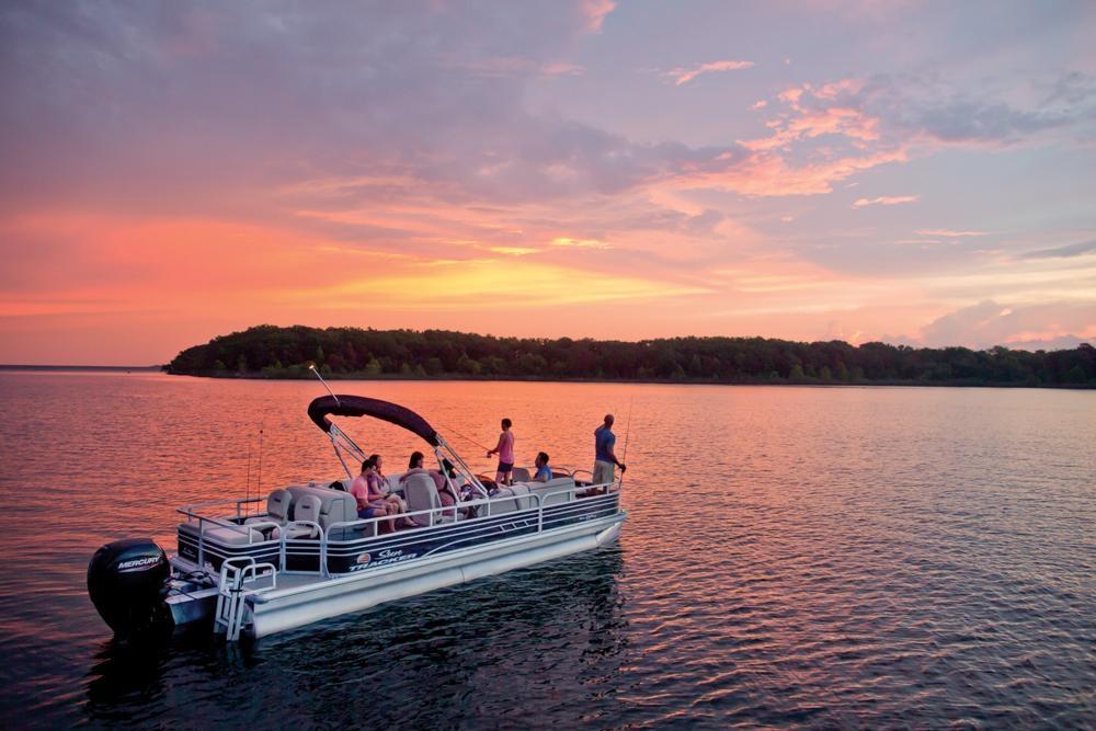 2021 Sun Tracker Fishin' Barge 24 DLX on serene lake at sunset.