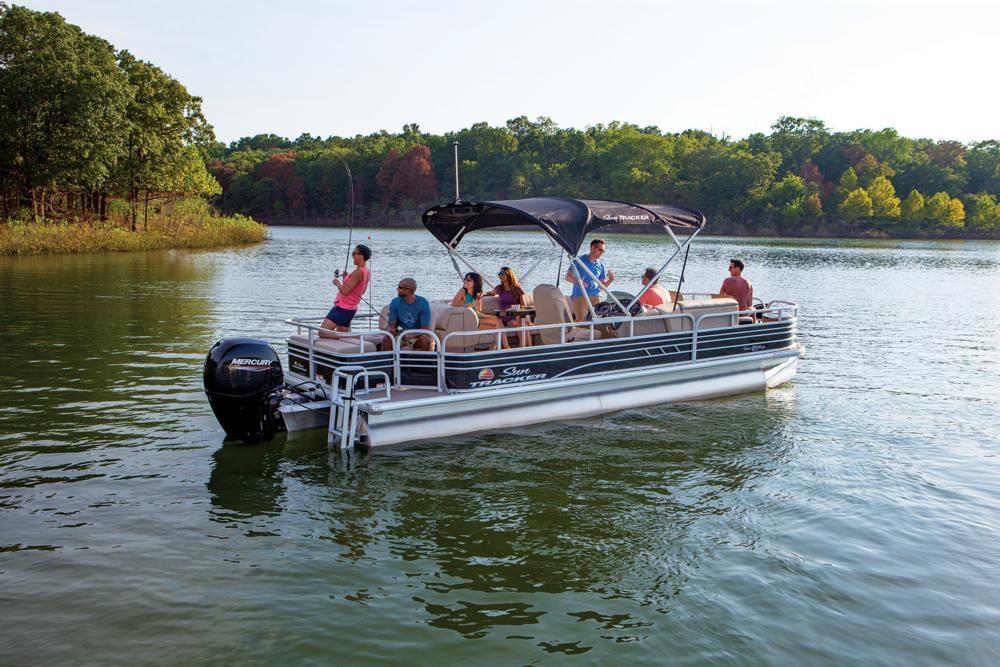 2021 Sun Tracker Fishin' Barge 24 DLX pontoon boat on a scenic lake.