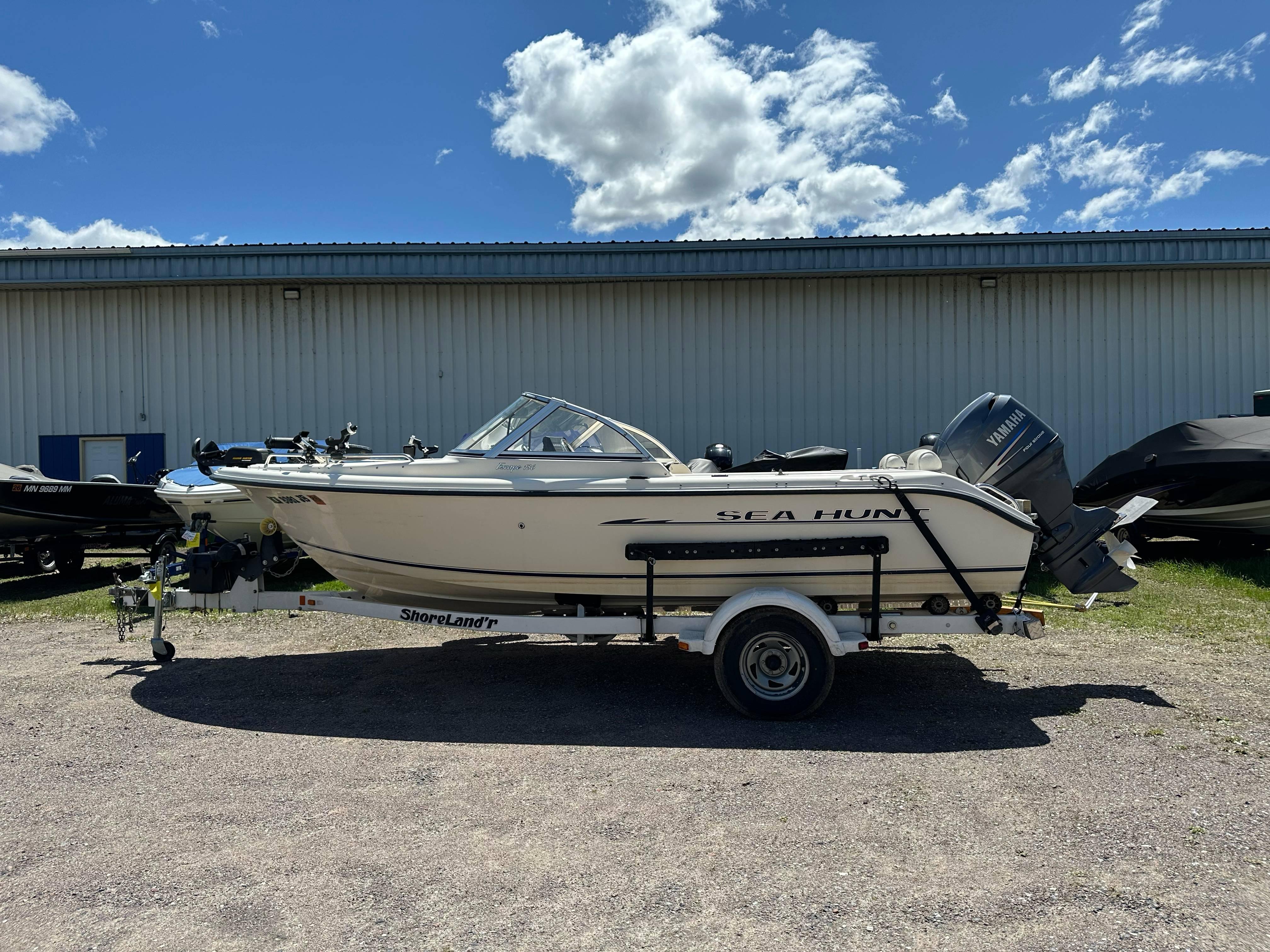 2003 Sea Hunt Escape 186 boat on trailer, parked outdoors under a blue sky.