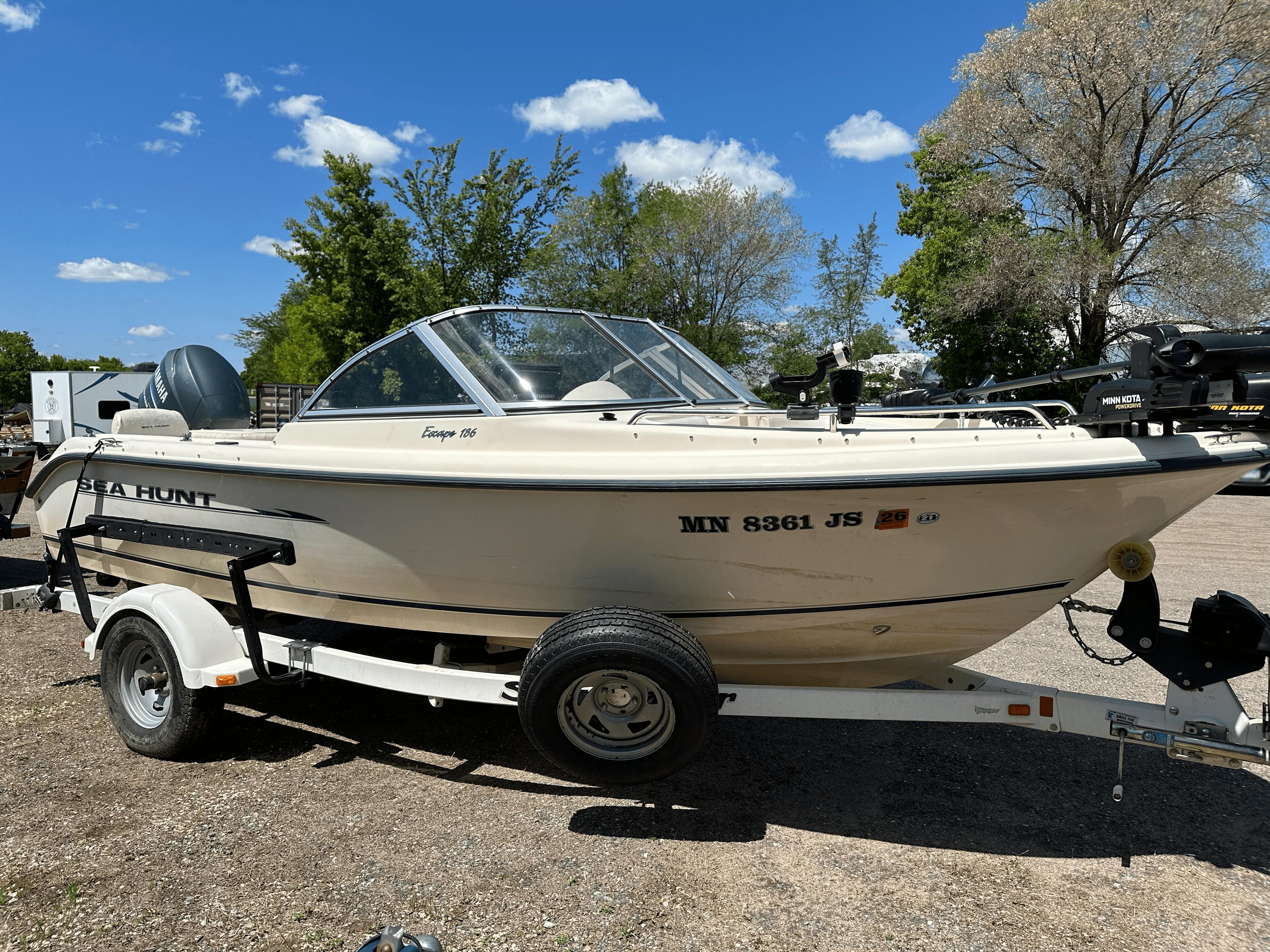 2003 Sea Hunt Escape 186 boat on trailer, parked outdoors under clear blue sky.