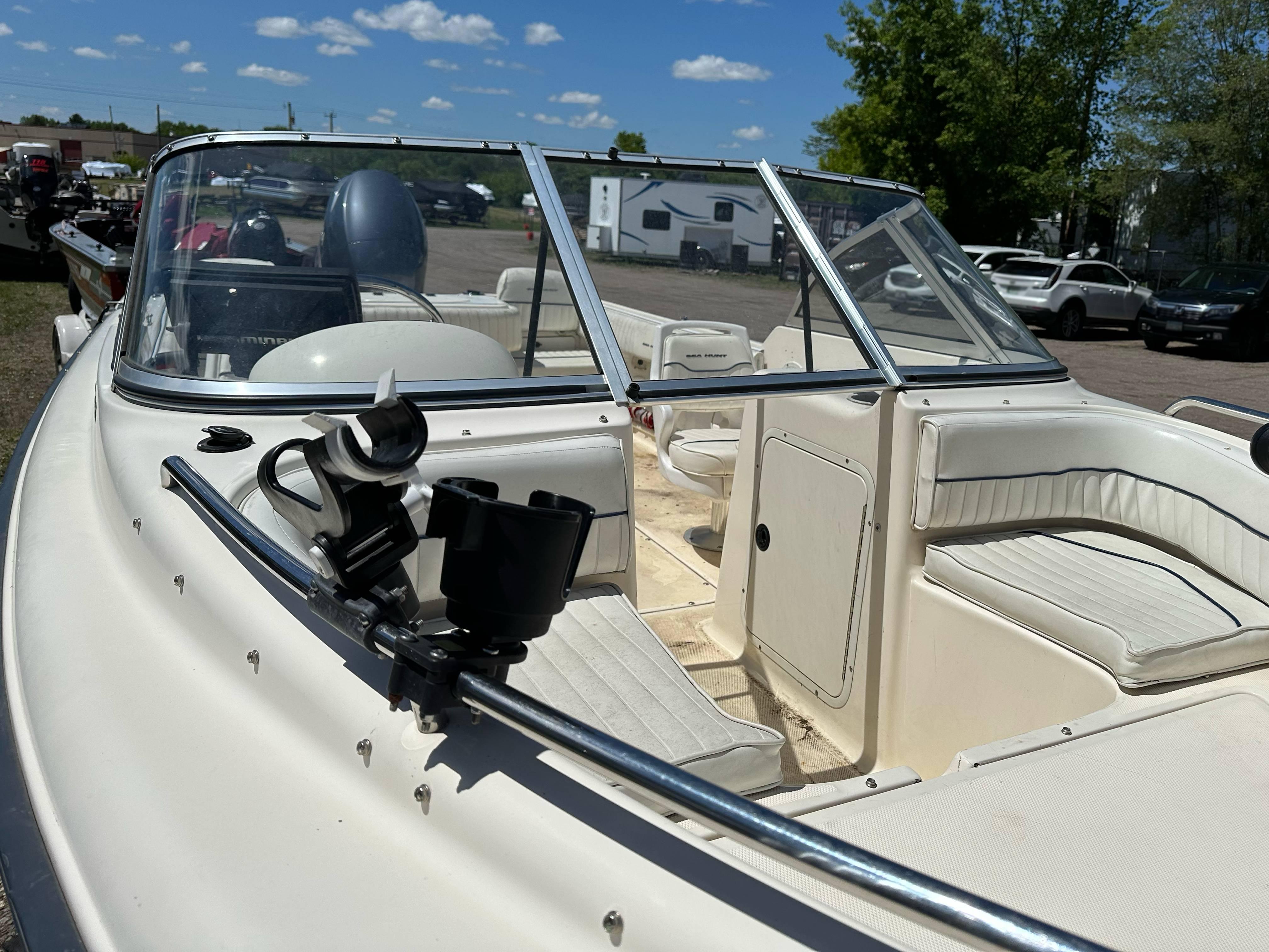 2003 Sea Hunt Escape 186 boat with open seating and windshield, parked outdoors under blue sky.