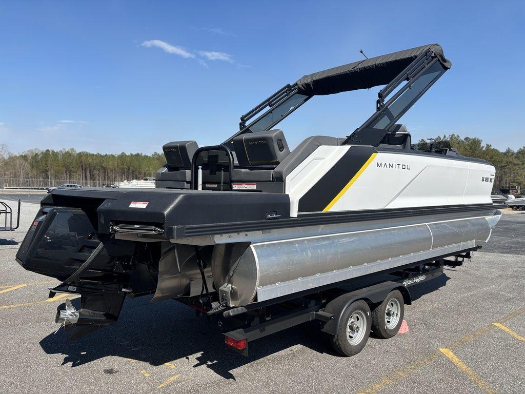 2023 Manitou Explore 22 Max Bench pontoon boat on trailer, parked outdoors.