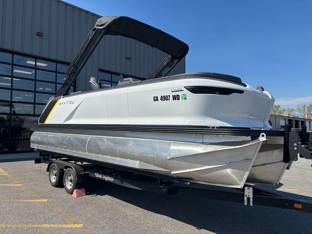 2023 Manitou Explore 22 Max Bench pontoon boat on trailer, parked outdoors.