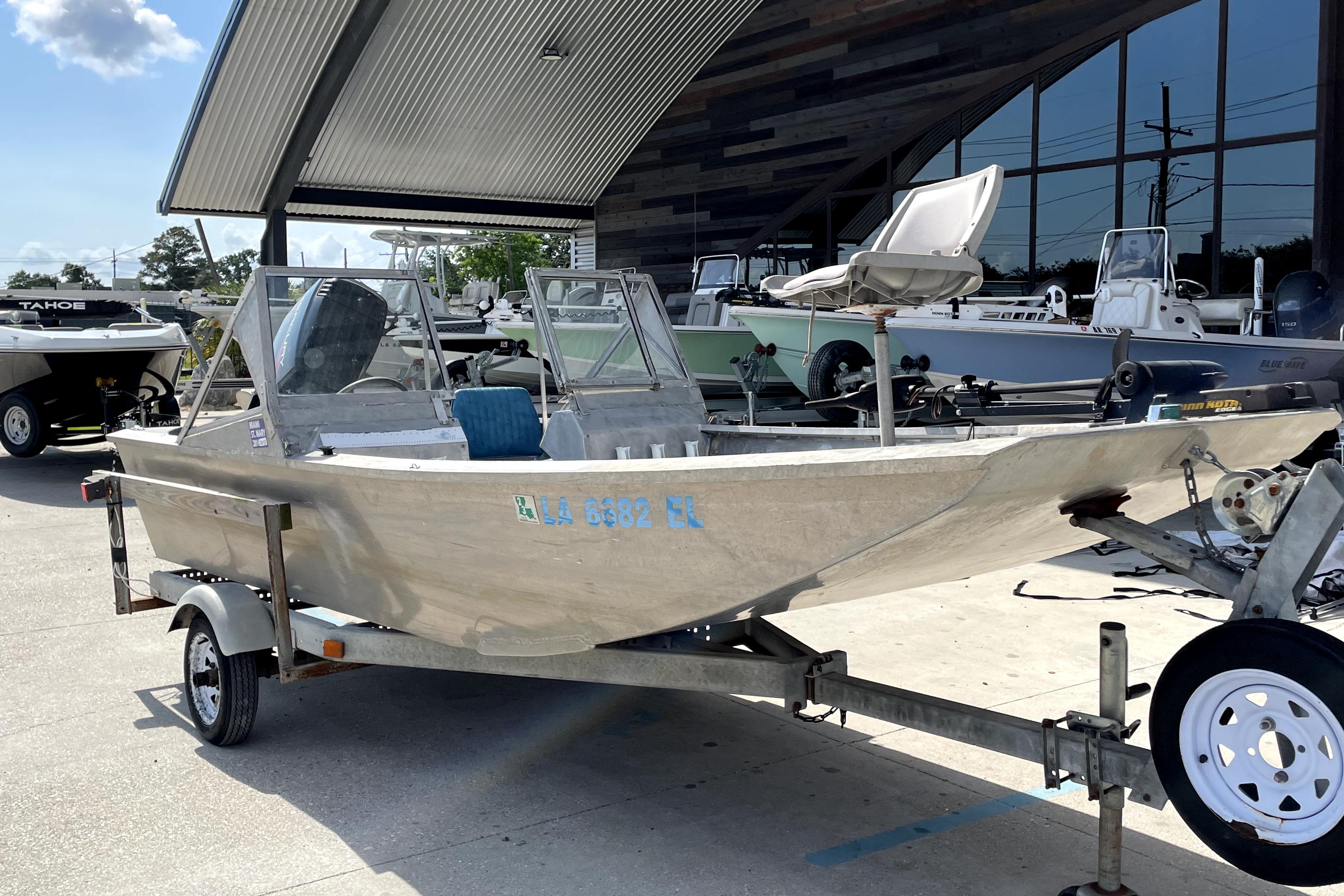 1994 Custom Aluminum 15 boat on trailer, parked outside a showroom.