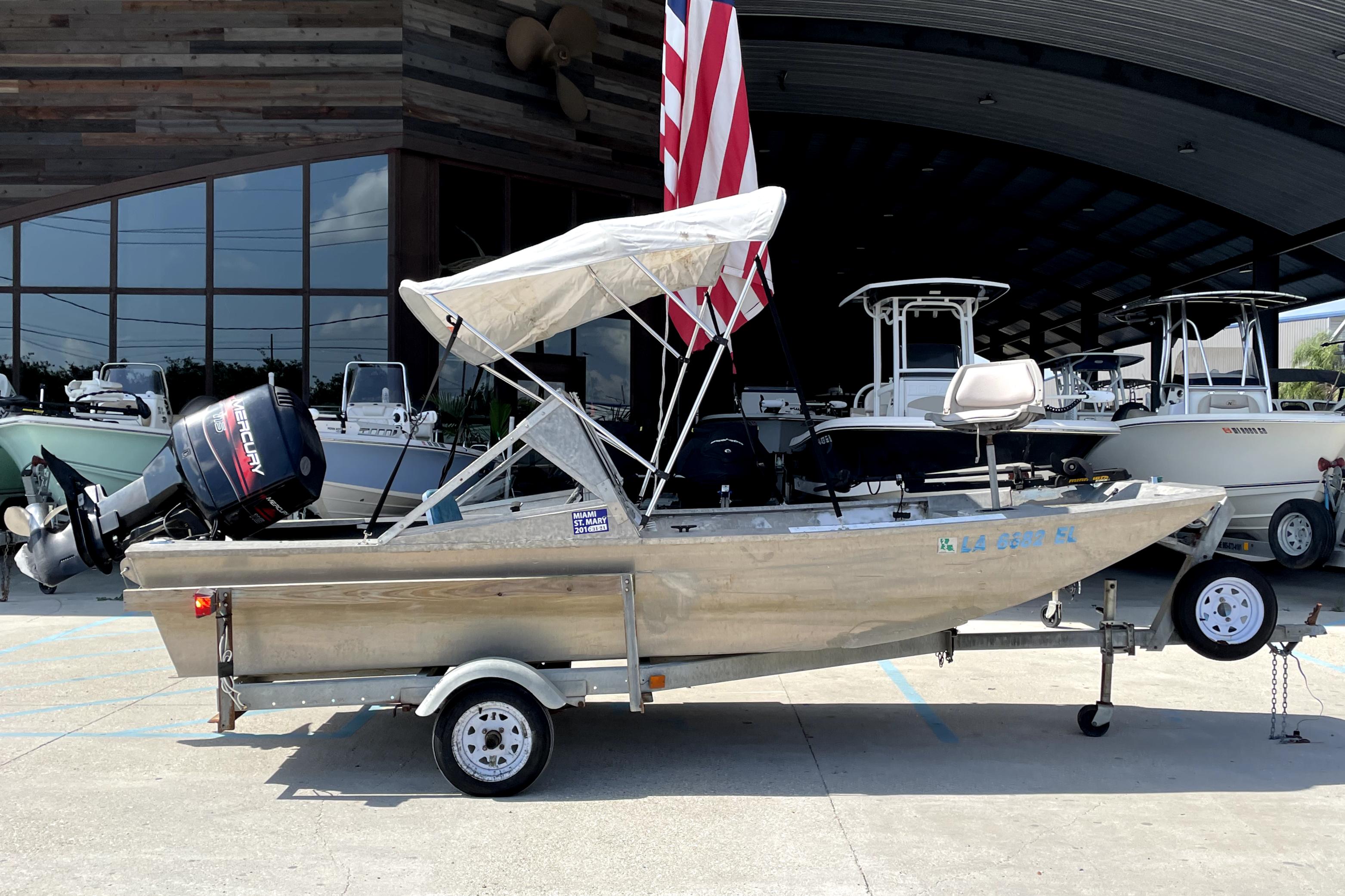 1994 Custom Aluminum 15 boat on trailer, with canopy and outboard motor, parked outdoors.