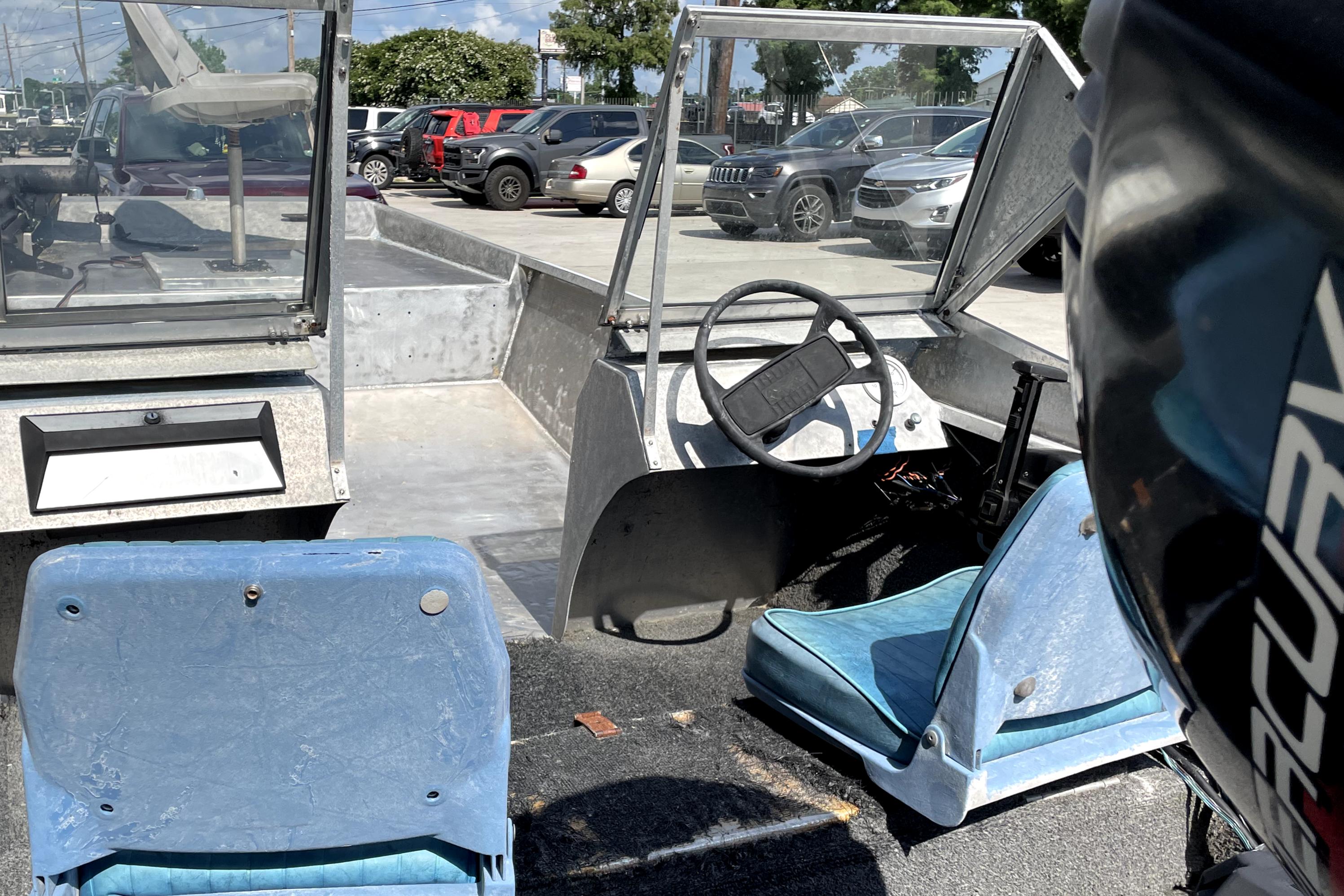 Interior of a 1994 Custom Aluminum 15 boat with blue seats and steering wheel.