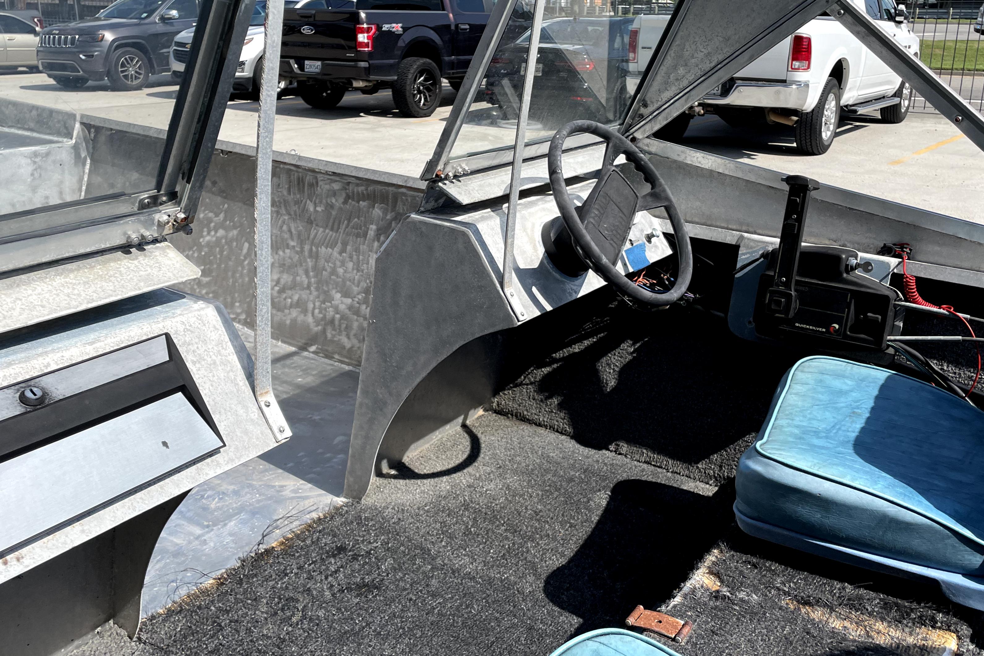 Interior of a 1994 Custom Aluminum 15 boat with steering wheel and blue seats.